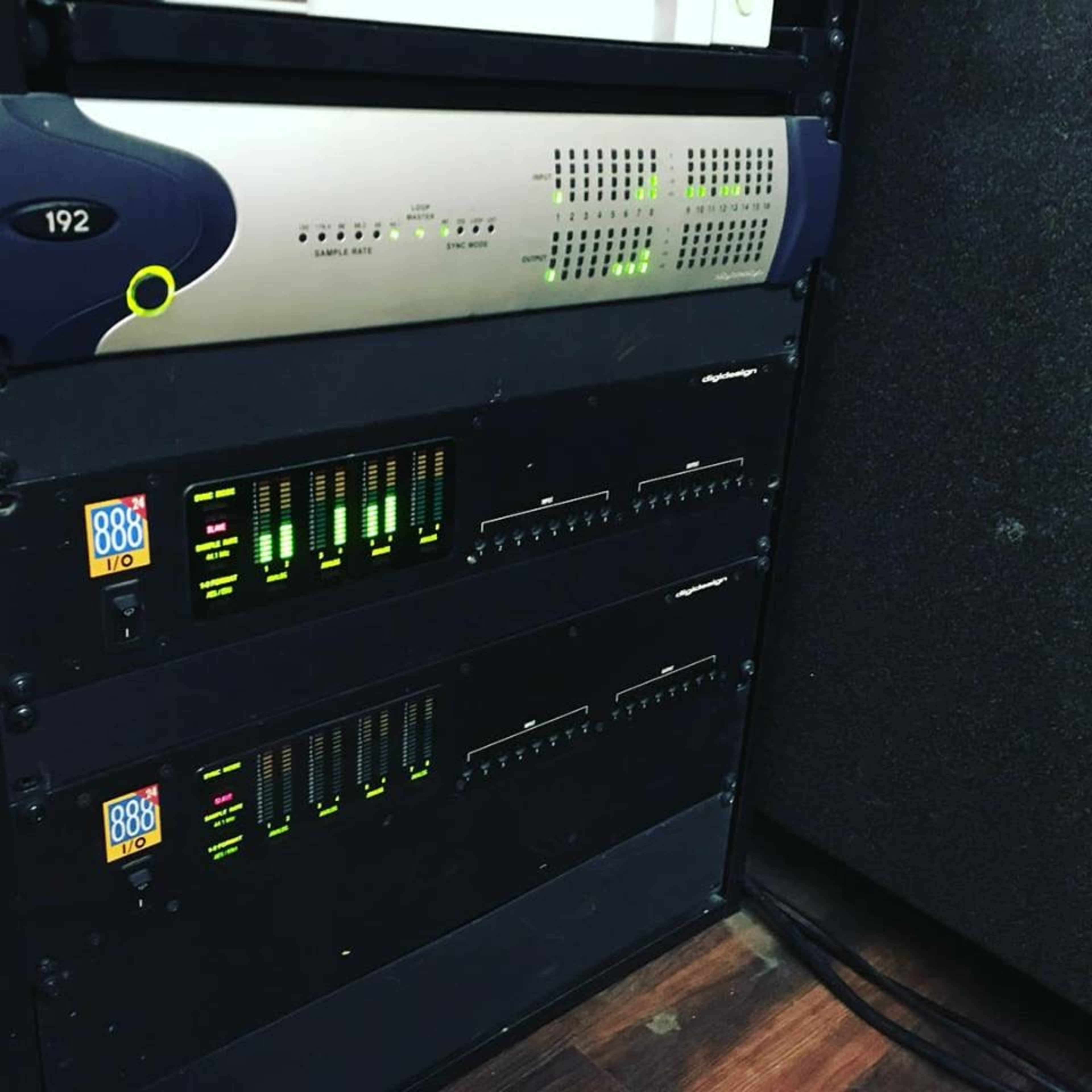 The image shows a rack of audio equipment featuring various signal processors and level meters.