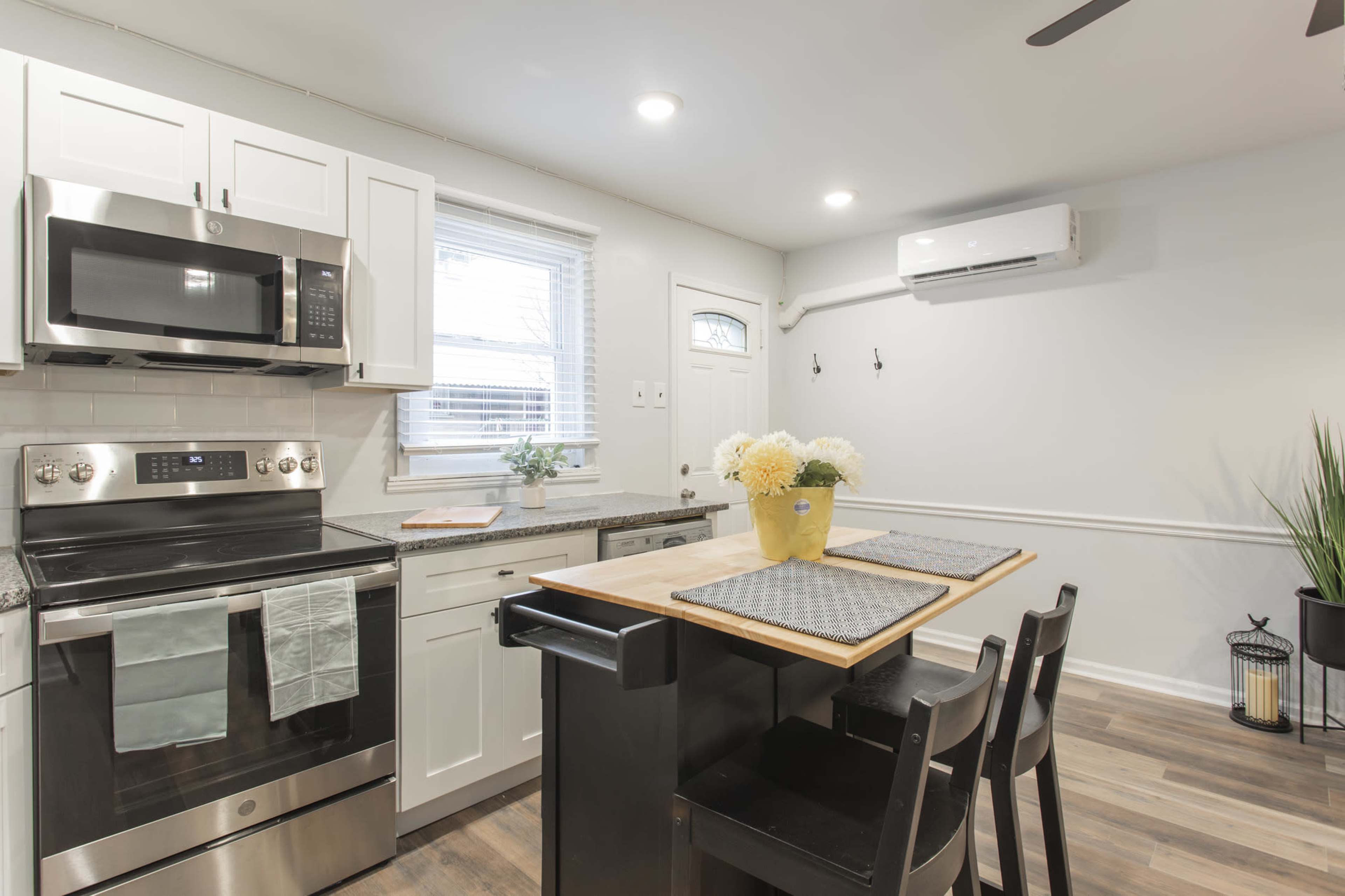 A modern kitchen features stainless steel appliances, a countertop with bar seating, and a window with light filtering through.