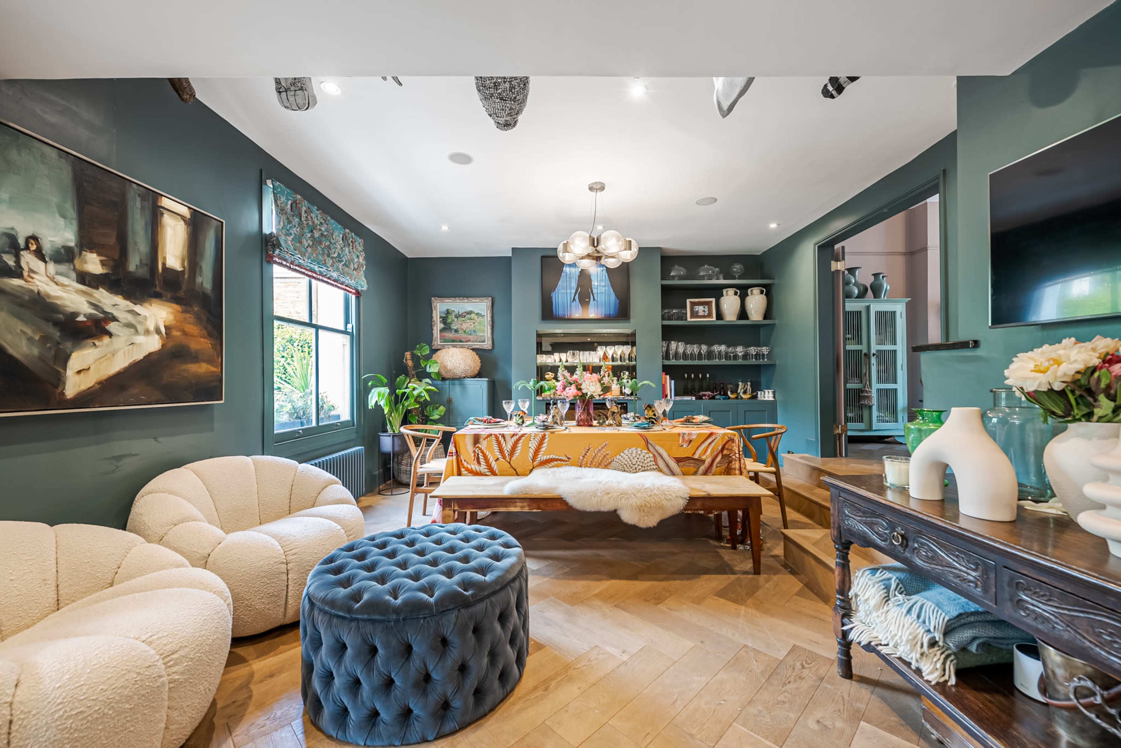 A cozy living space features plush seating, a wooden dining table adorned with decorative items, and a well-stocked bar area.