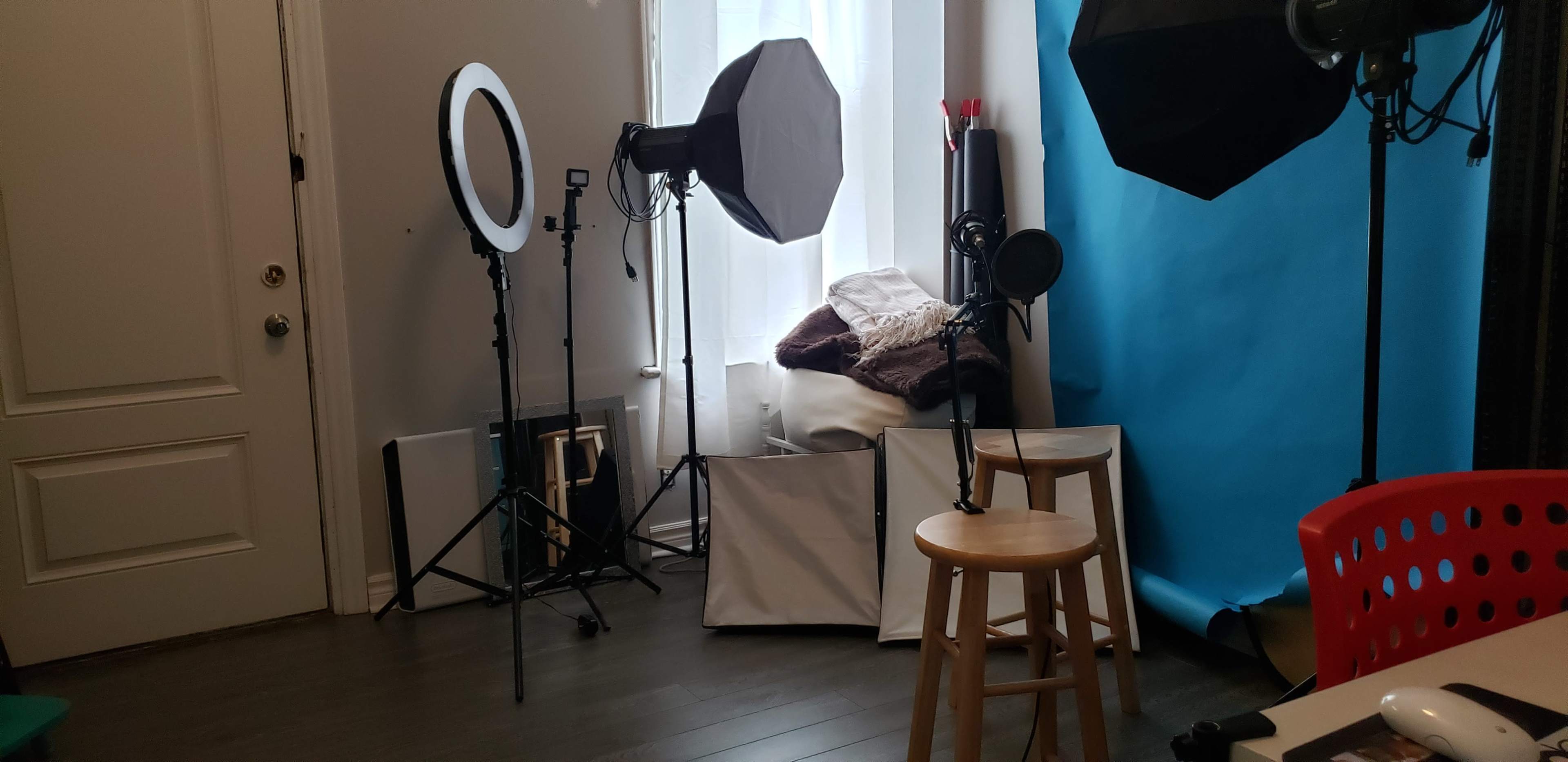 The image displays a photography setup featuring lighting equipment, a backdrop, and a stool arranged in a room.