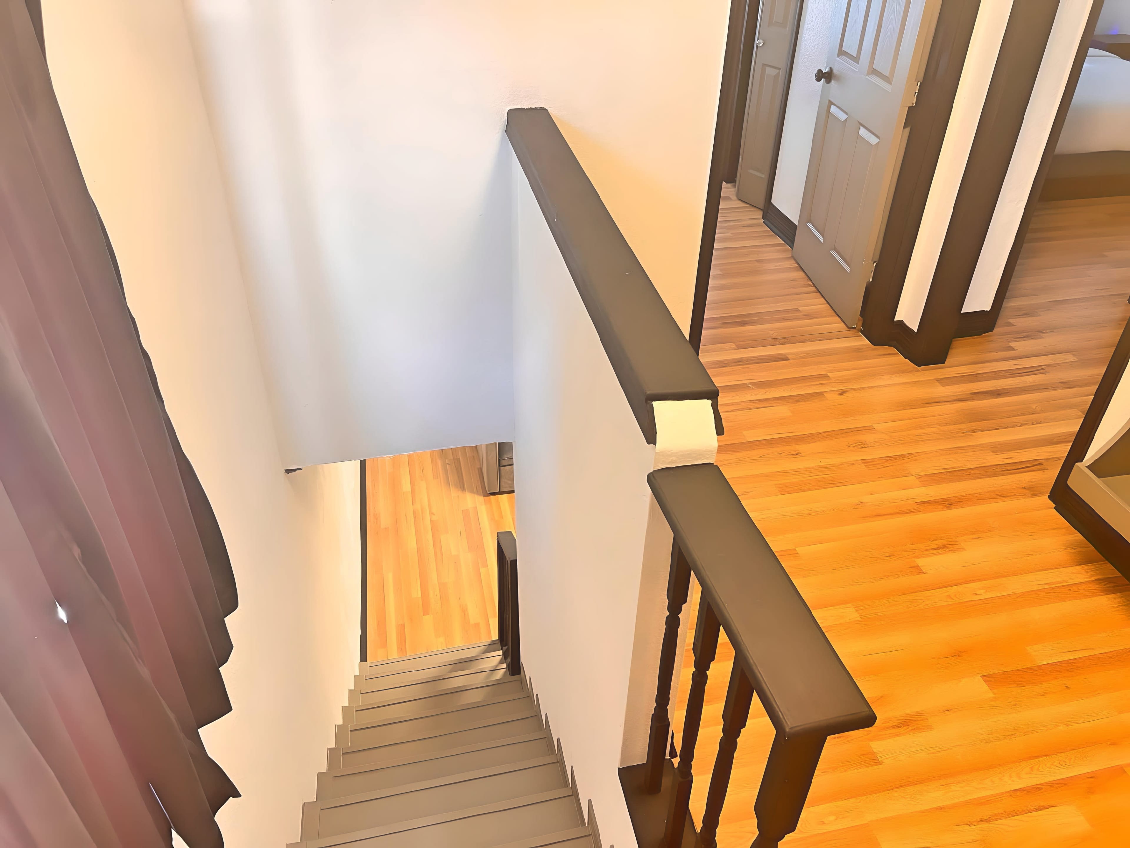 The image shows a staircase leading down from a landing, with doorways visible on either side of the hall at the top.