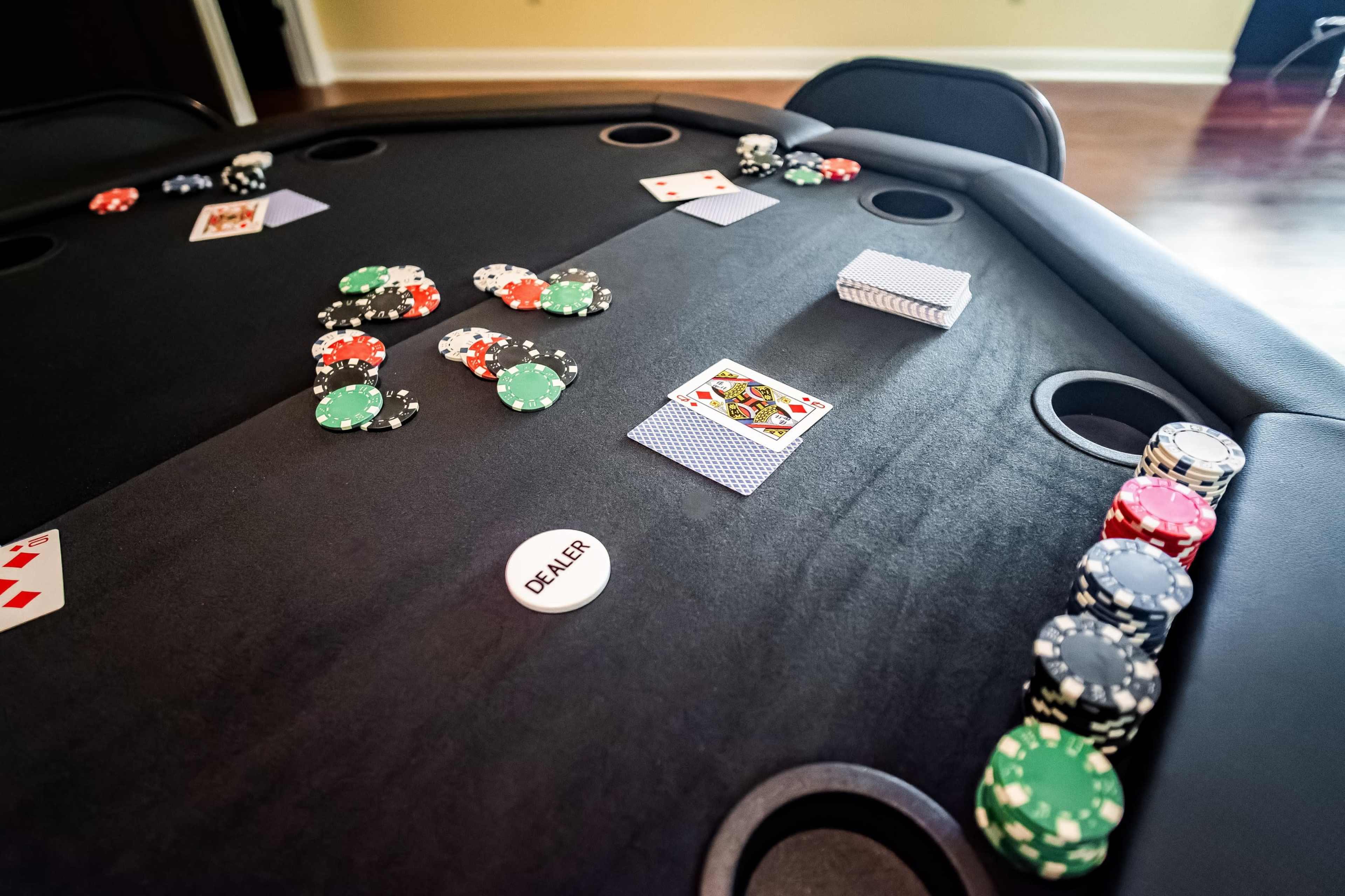 A poker table is set up with various colored chips and playing cards, including a visible "DEALER" button.