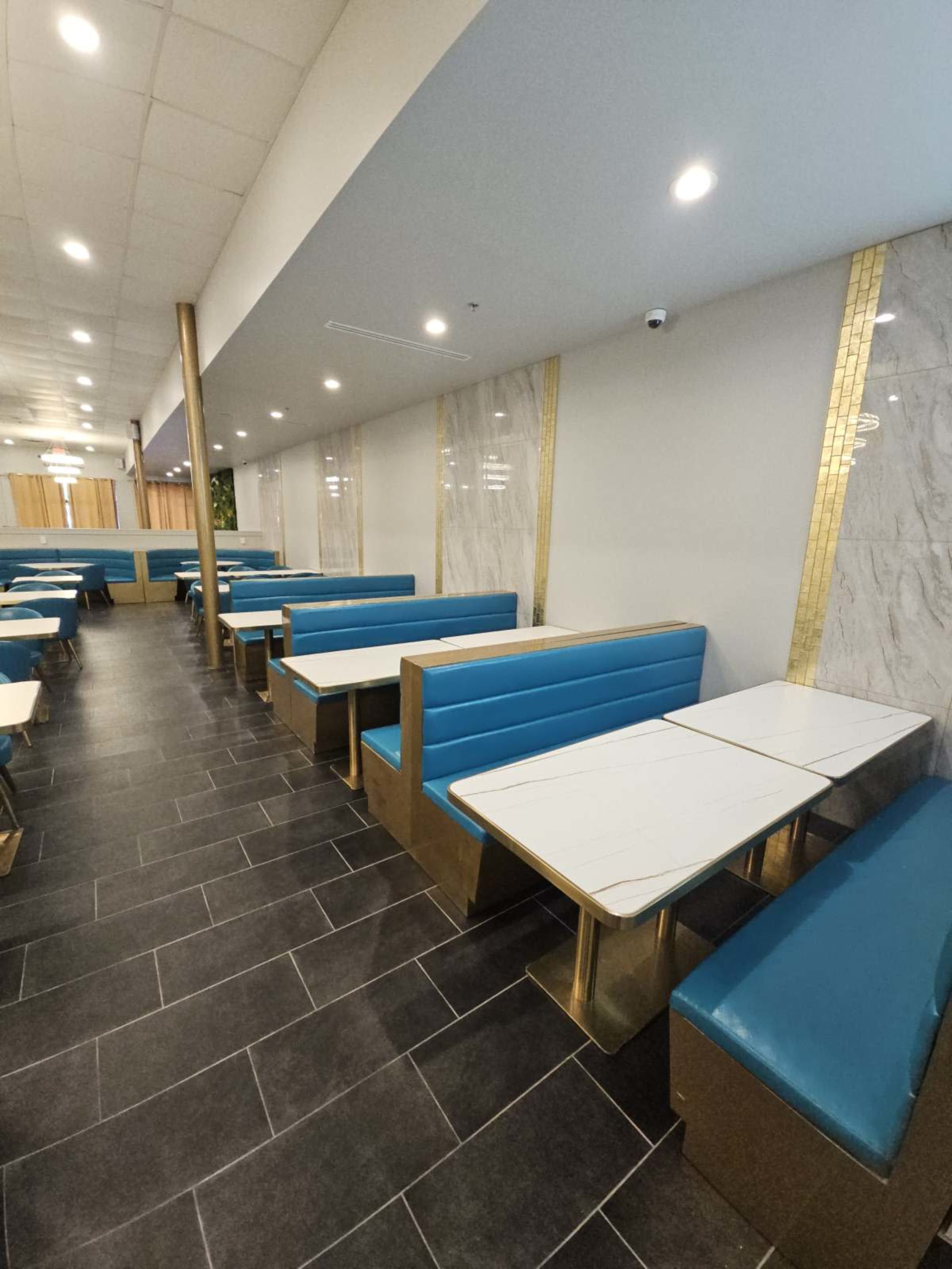 The image shows an interior of a restaurant with blue and white booth seating arranged along a long, tiled corridor.