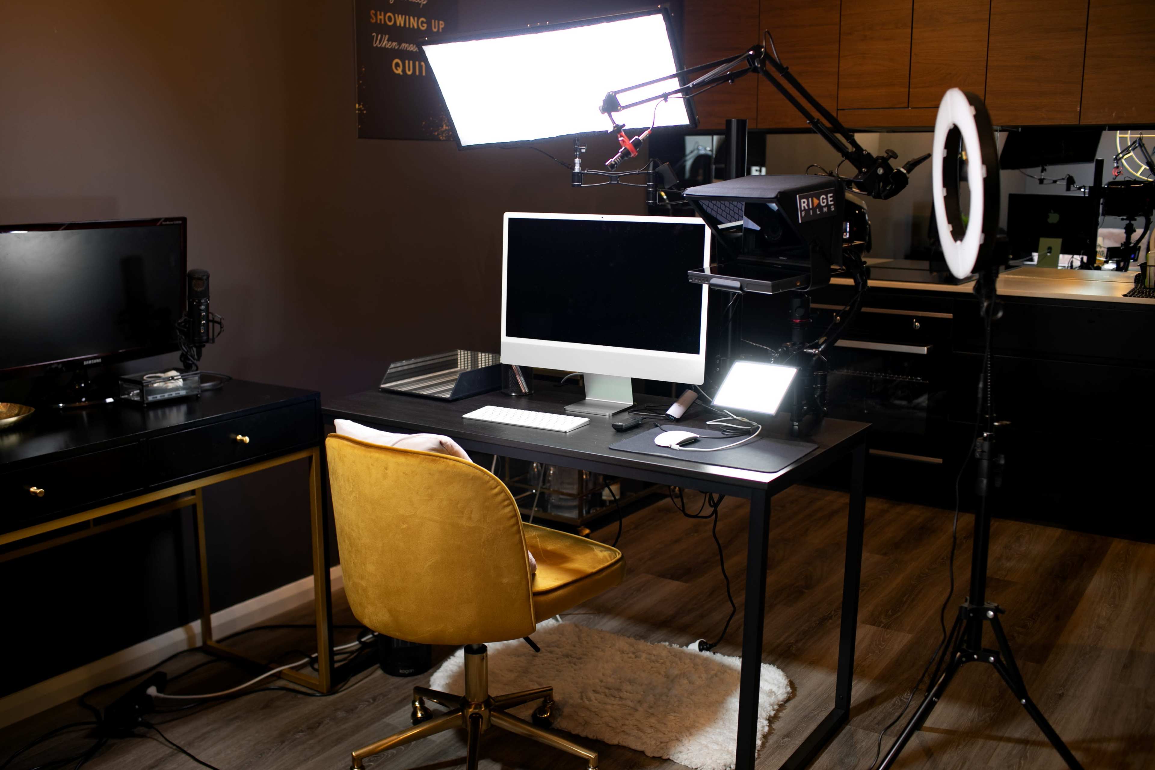 A modern workspace featuring a black desk with a computer, a yellow chair, and professional lighting equipment.