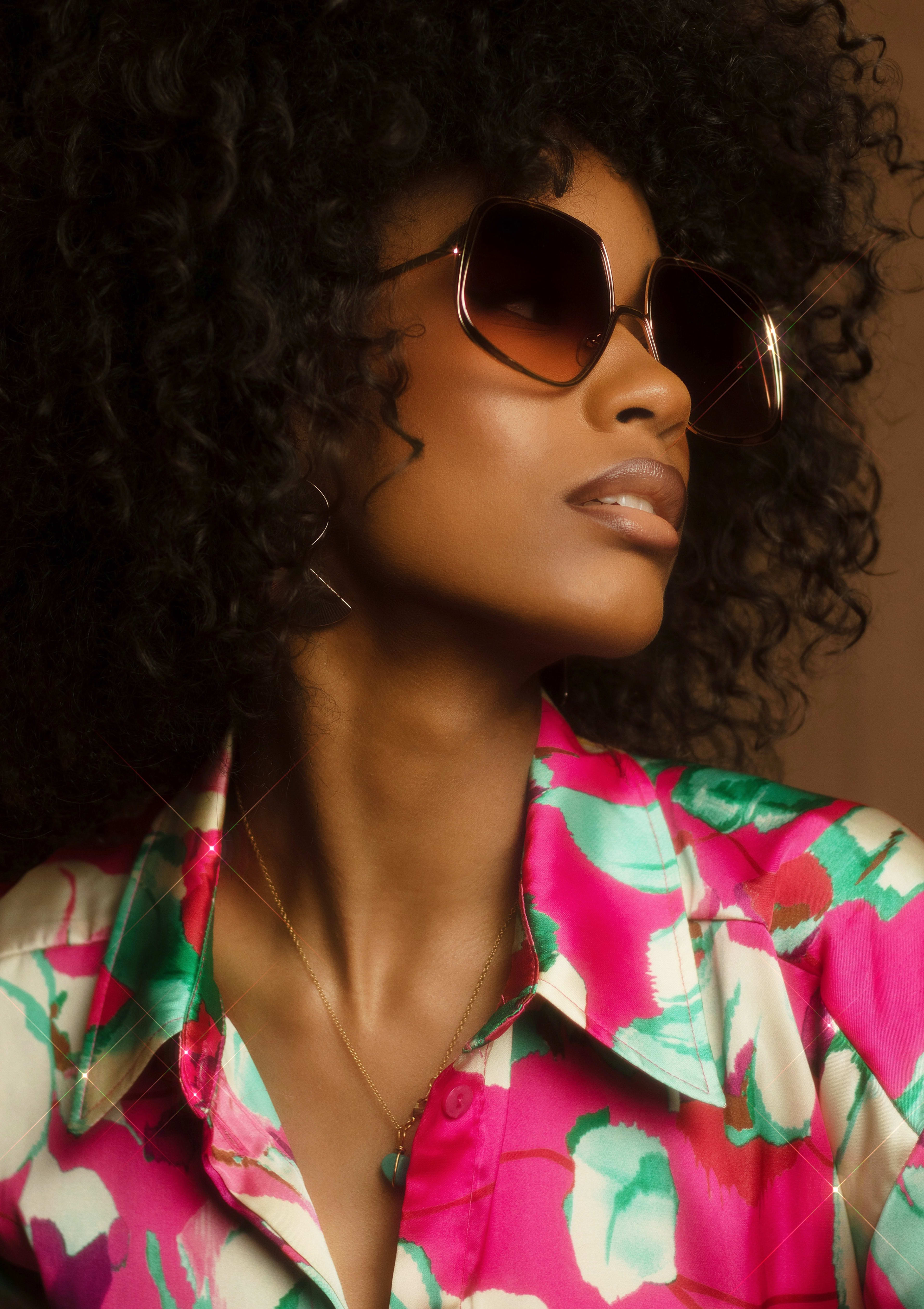 A photo shoot of a person in a pink and green-collared shirt wearing sunglasses.
