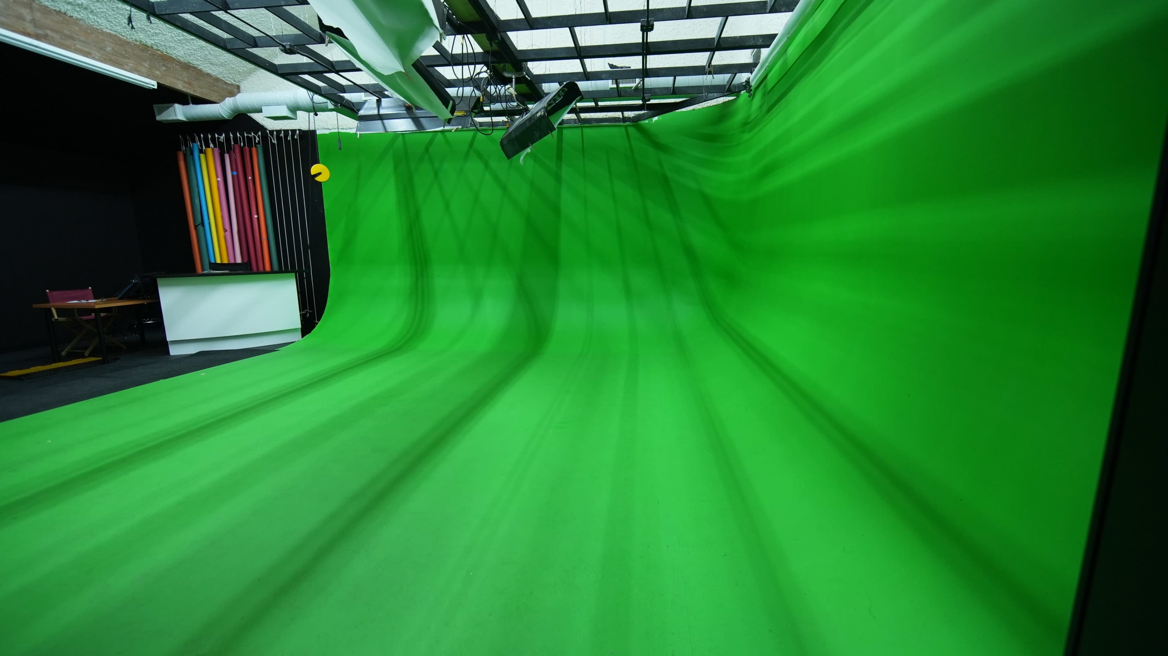 The image shows a studio with a large, undulating green screen that serves as a backdrop.