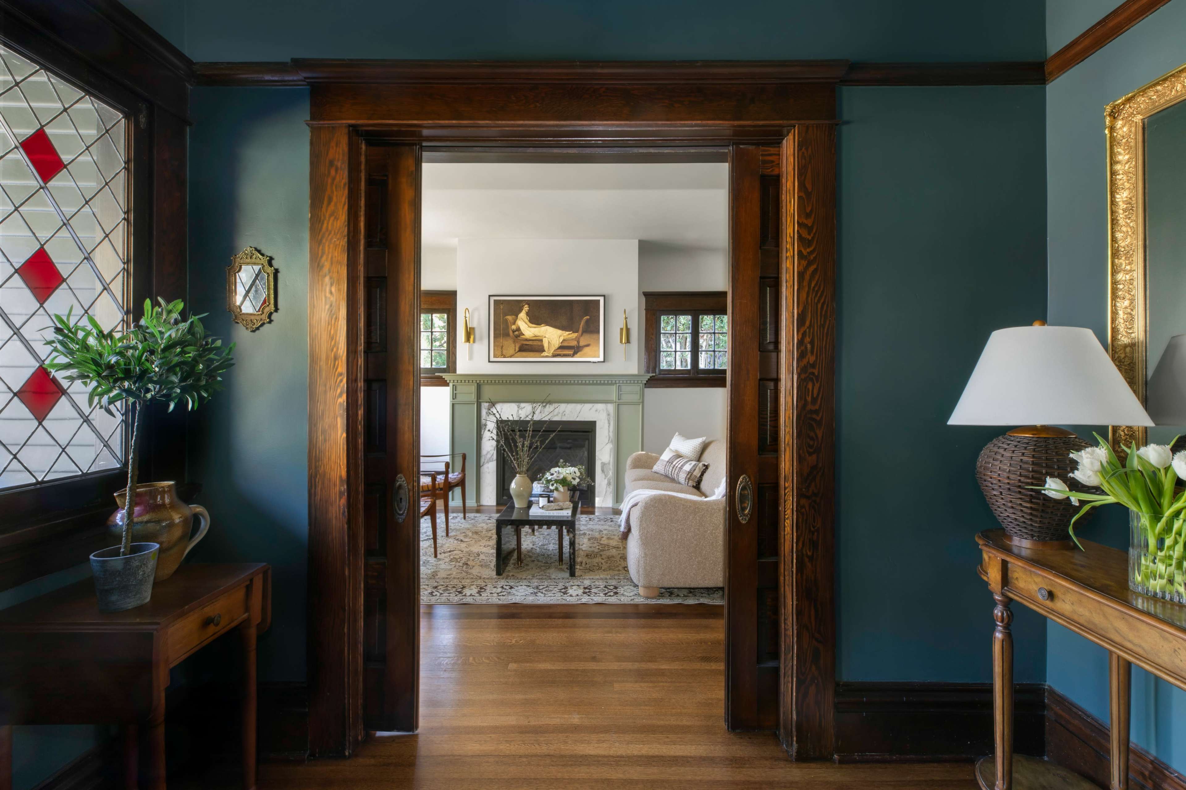A view from a hallway with dark wood doors opening into a living room featuring a fireplace, a sofa, and a decorative rug.