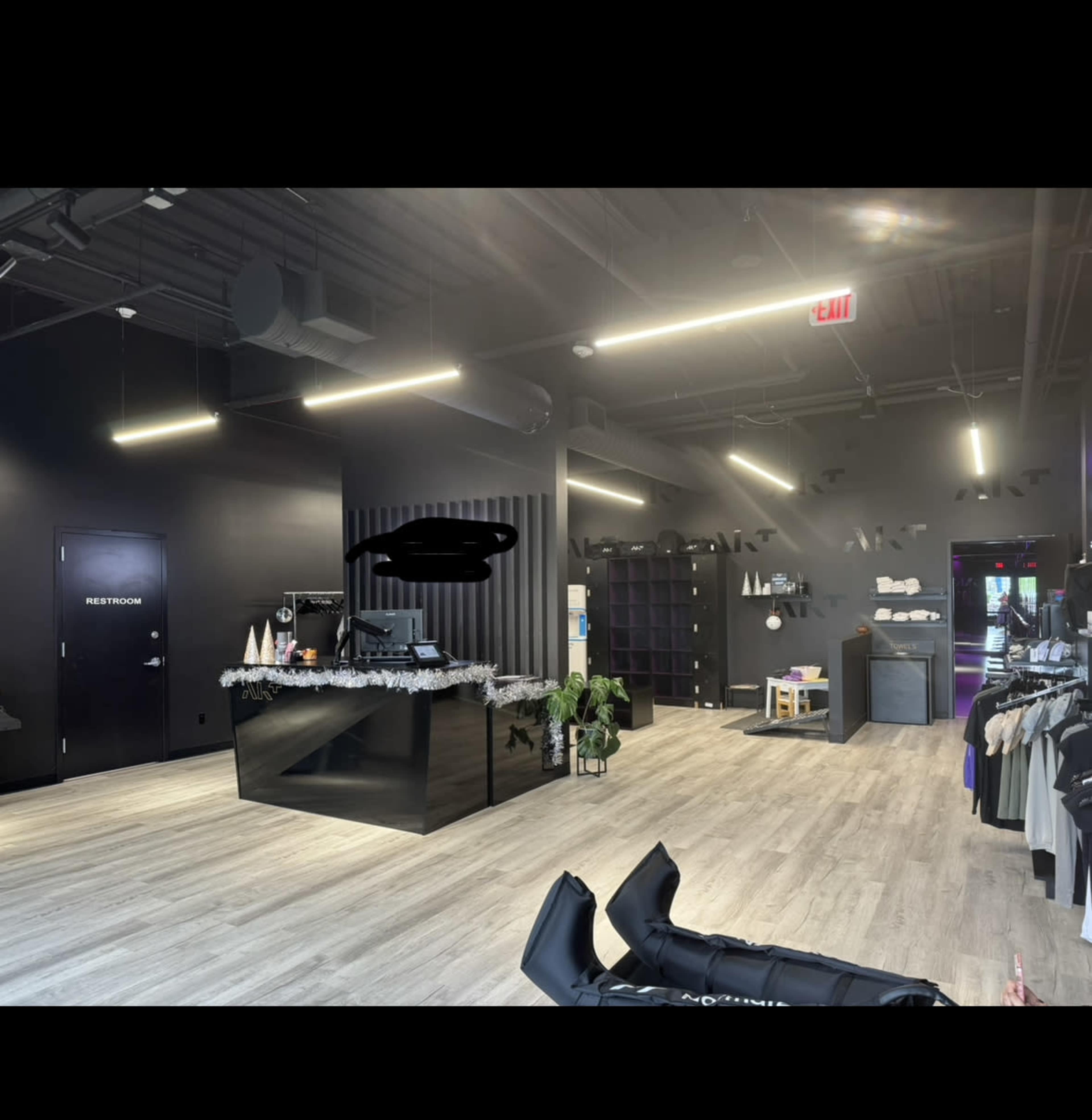 The interior of a modern retail space with a reception area, black walls, and a display of merchandise on the right.