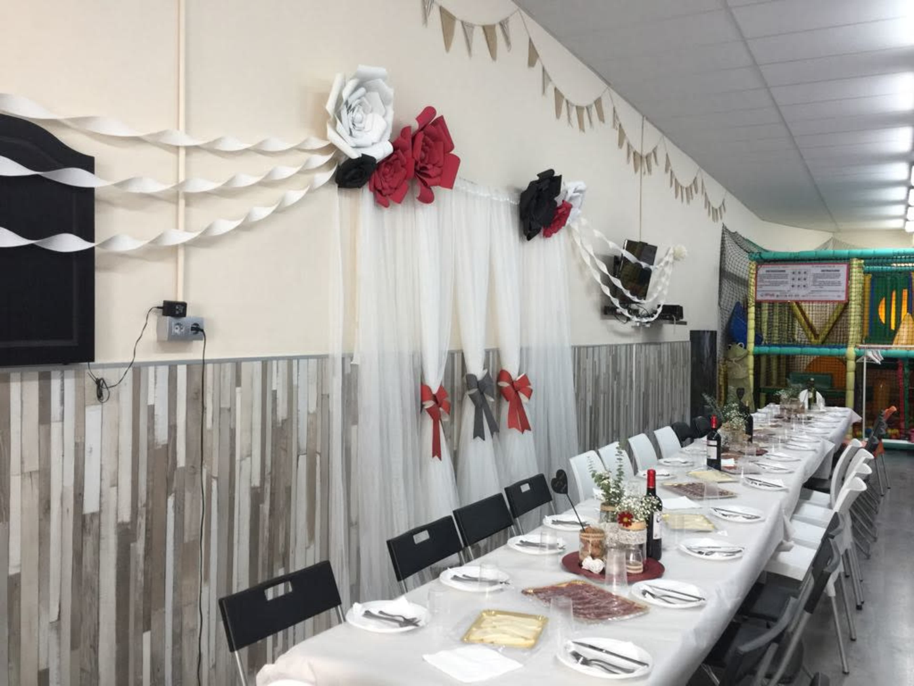 A long dining table is set in a decorated room with paper flowers and garlands on the walls.