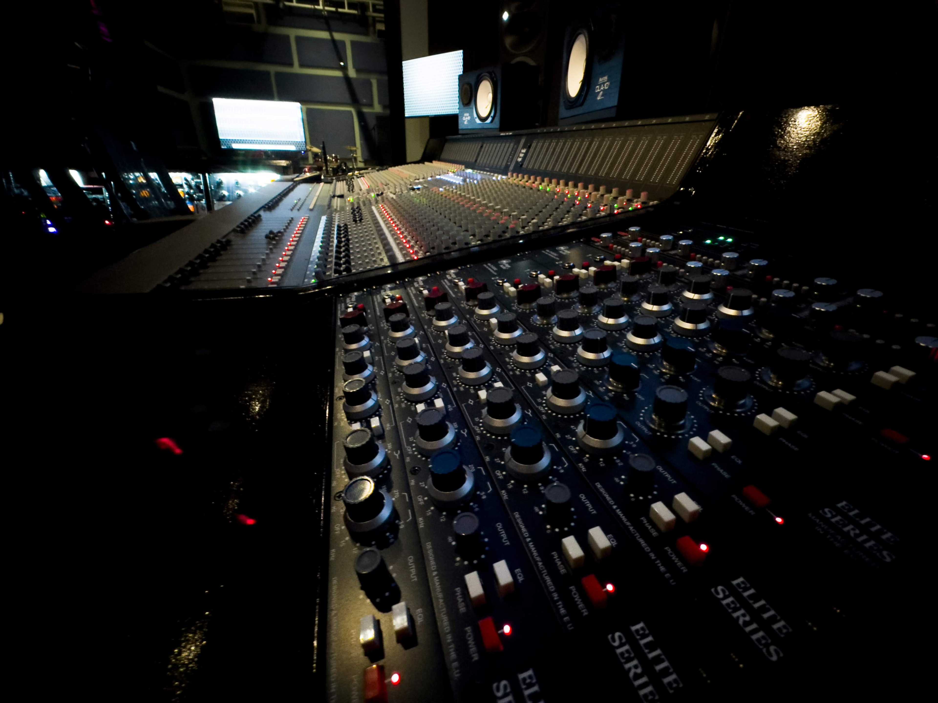 A close-up view of a recording studio mixing console with various knobs and sliders.