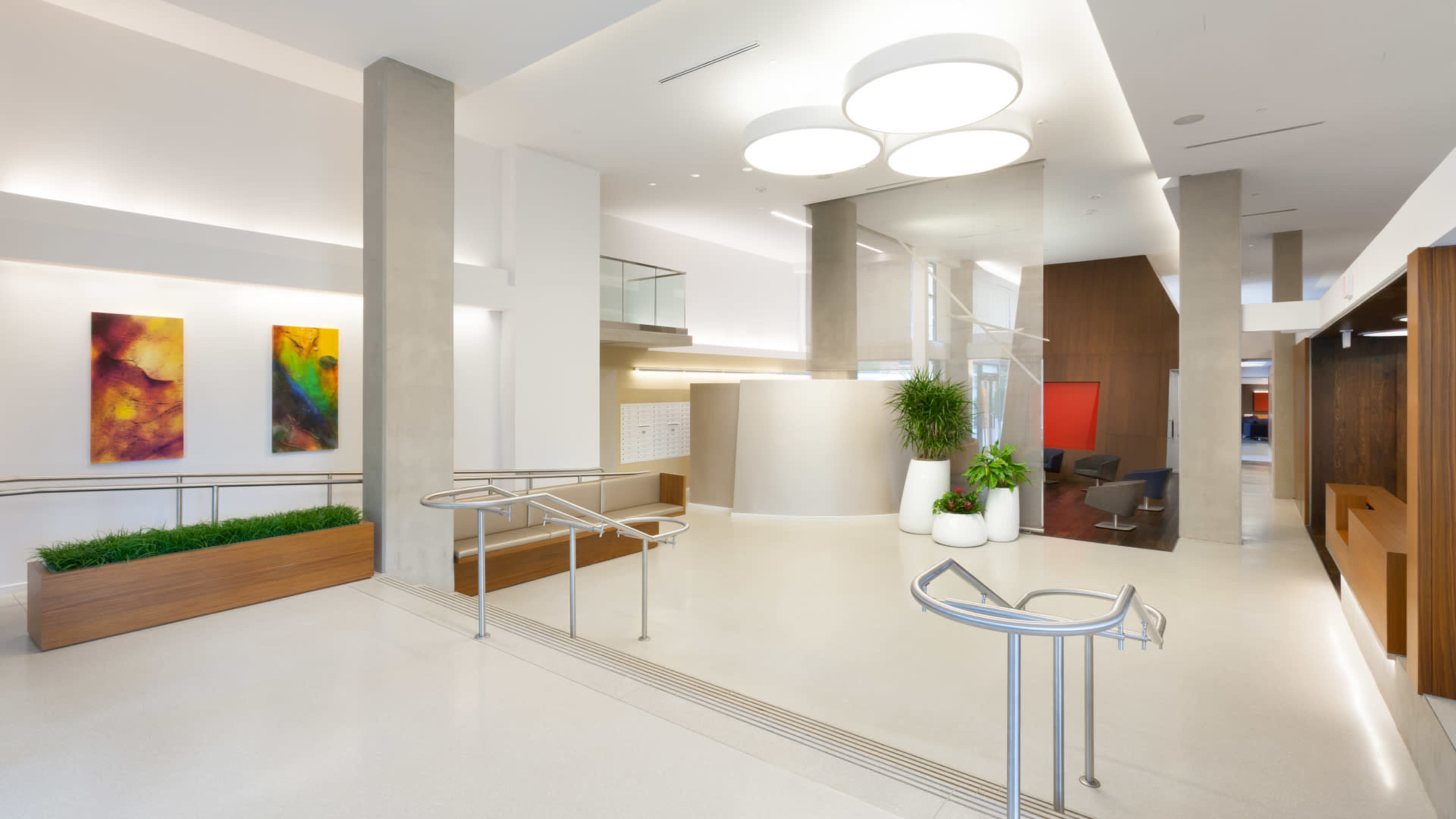 A modern lobby area with polished flooring, large circular light fixtures, and colorful abstract art on the walls.