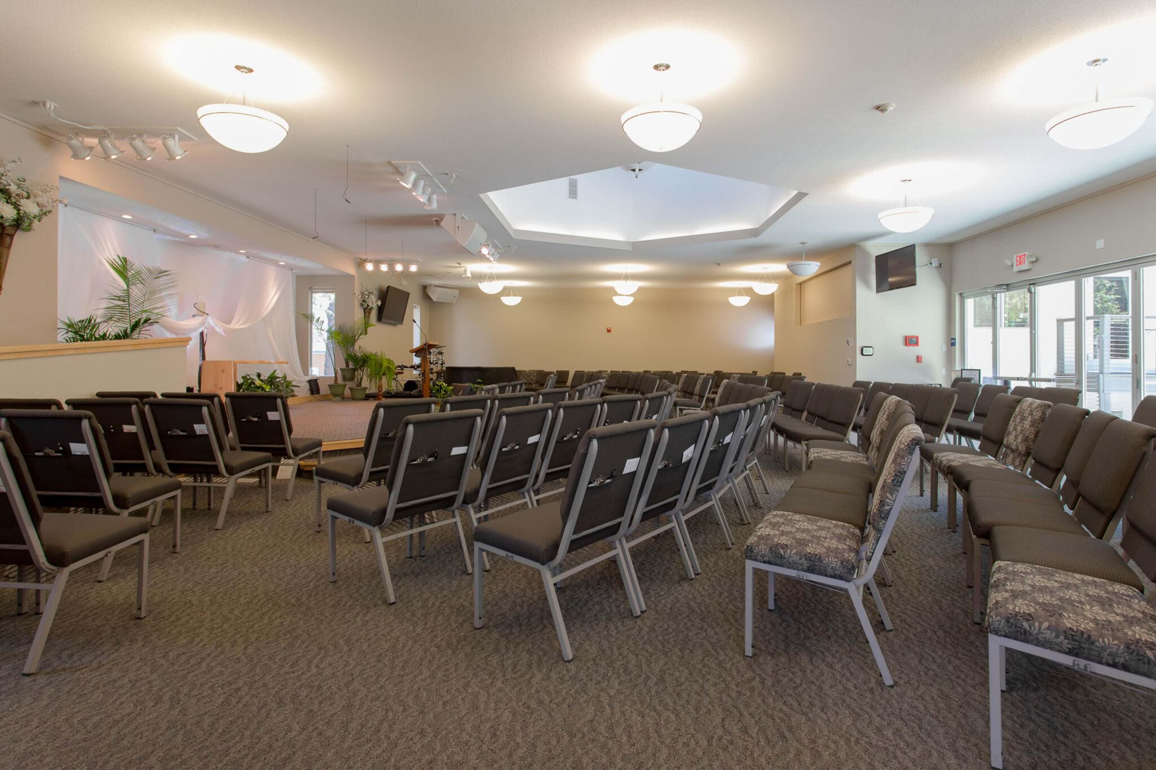 A spacious interior of a gathering hall with rows of chairs arranged around a central stage area.
