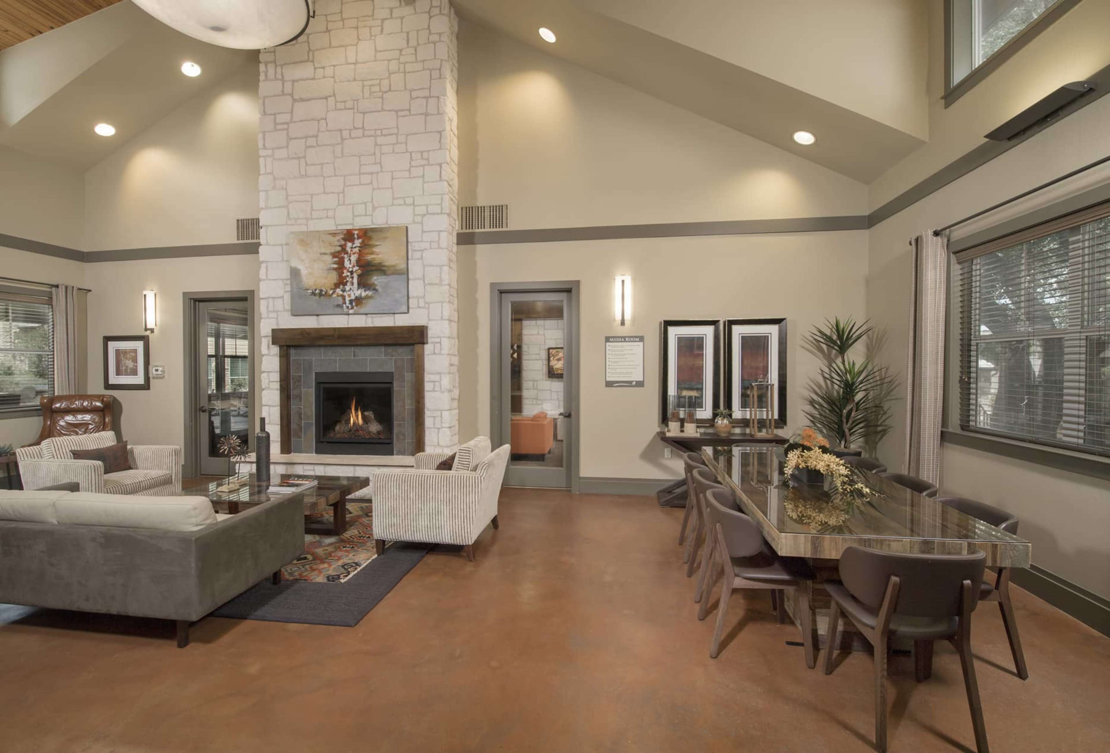A modern living area with a stone fireplace, a seating arrangement of sofas and chairs, and a dining table set for several people.