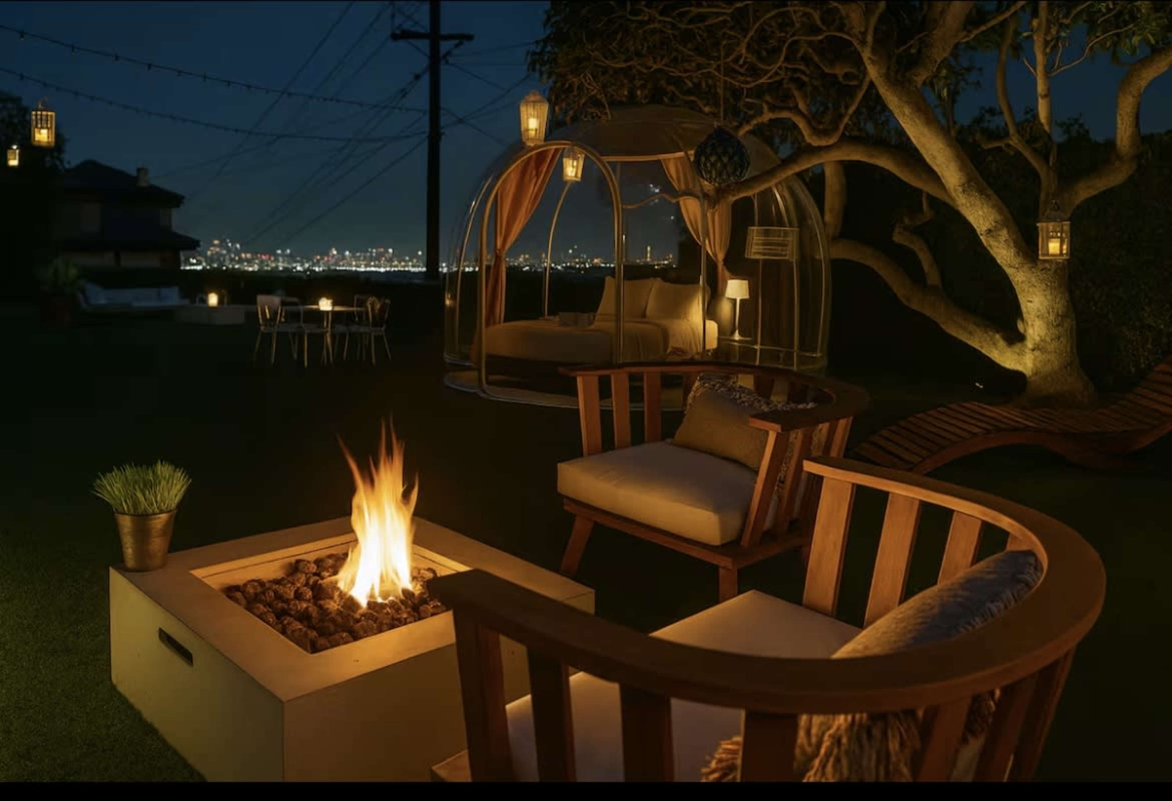 The image depicts a cozy outdoor seating area at night, featuring a fire pit surrounded by wooden chairs, a hanging chair, and city lights in the background.