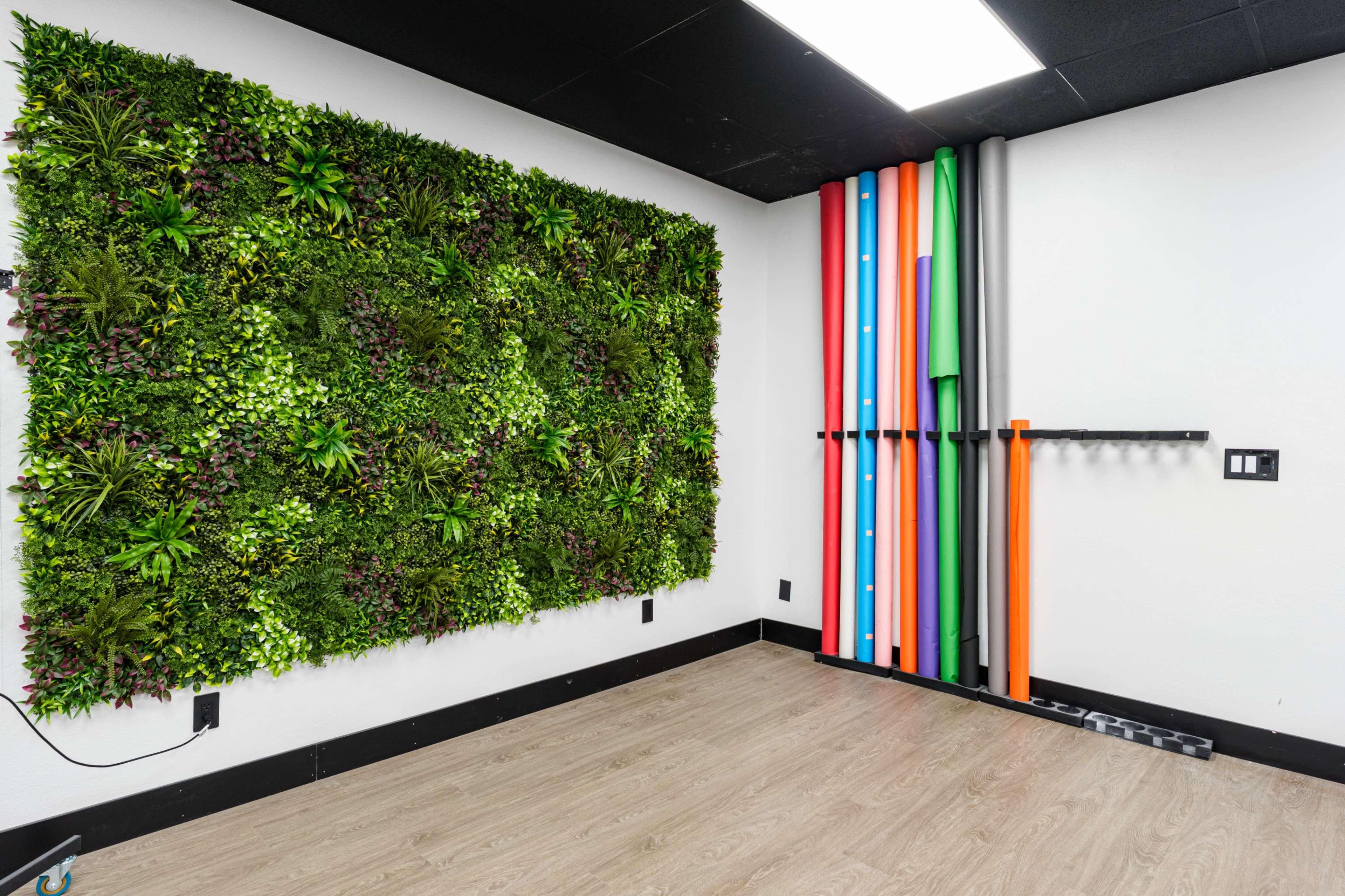 The image shows a room with a vertical garden on one wall and colorful pipes mounted on another wall.