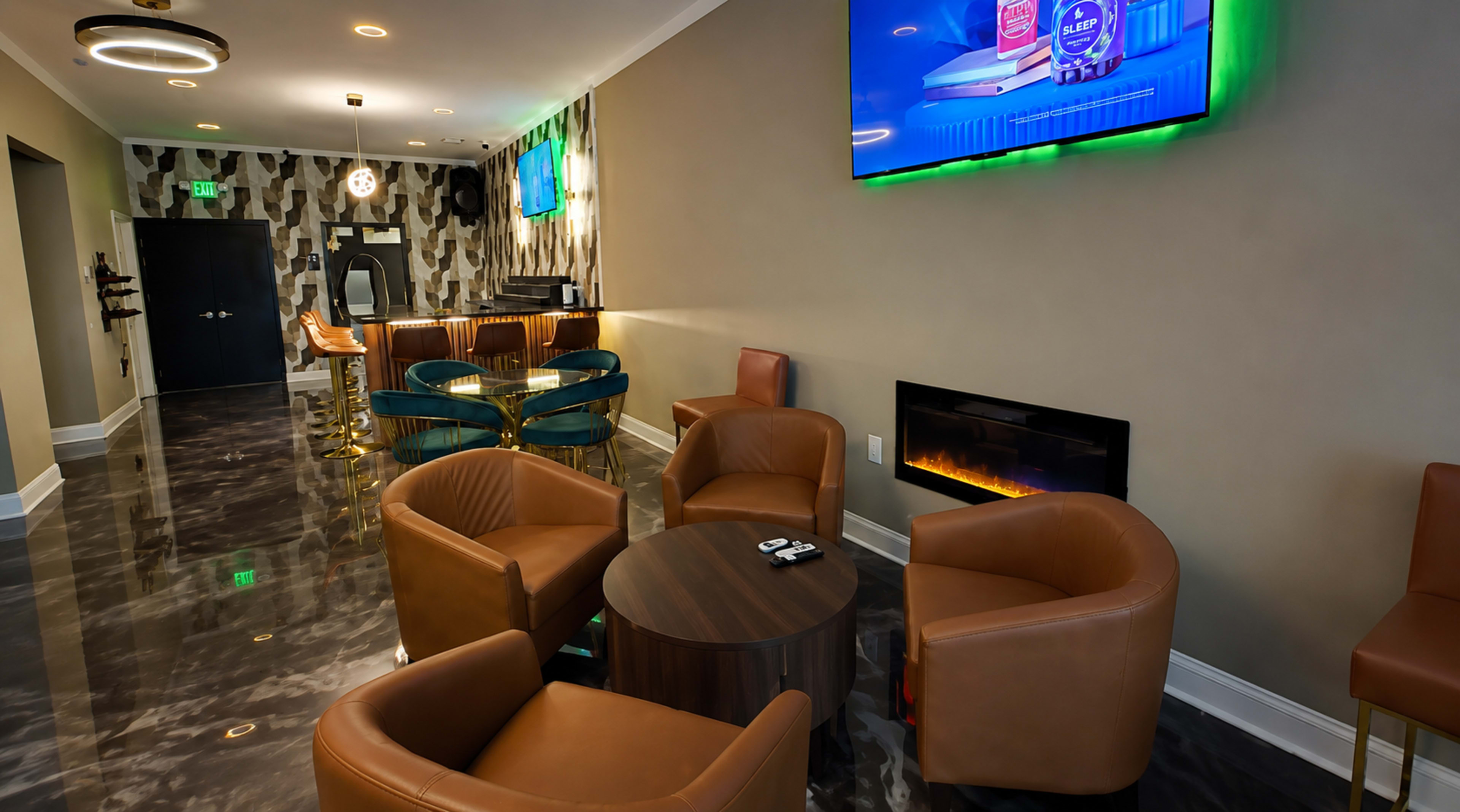 The image shows a modern lounge area with brown leather chairs arranged around a circular table, a wall-mounted television, and a stylish bar in the background.