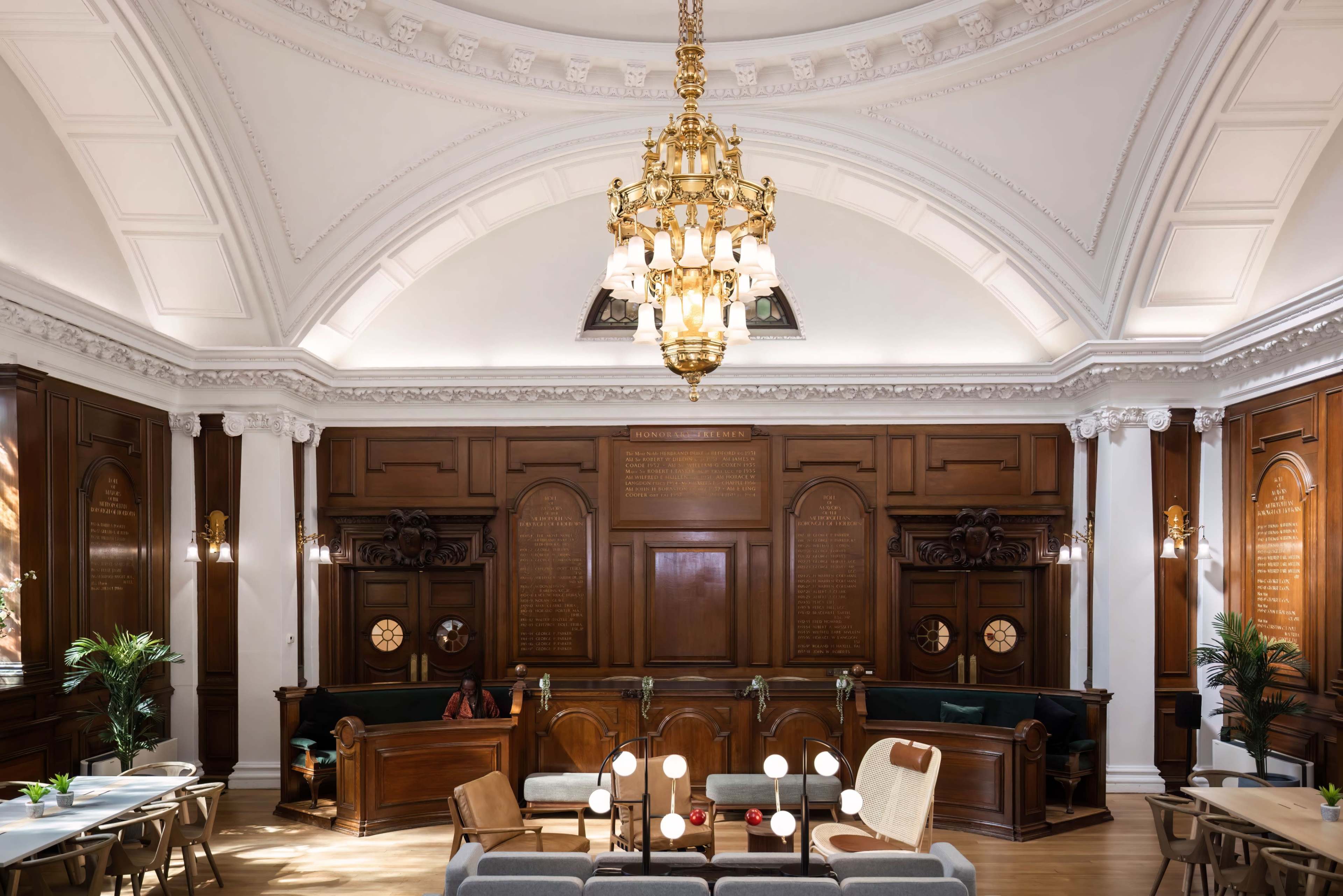 A spacious interior with ornate wood panels, a large chandelier, and a seating area featuring a mix of modern furniture.