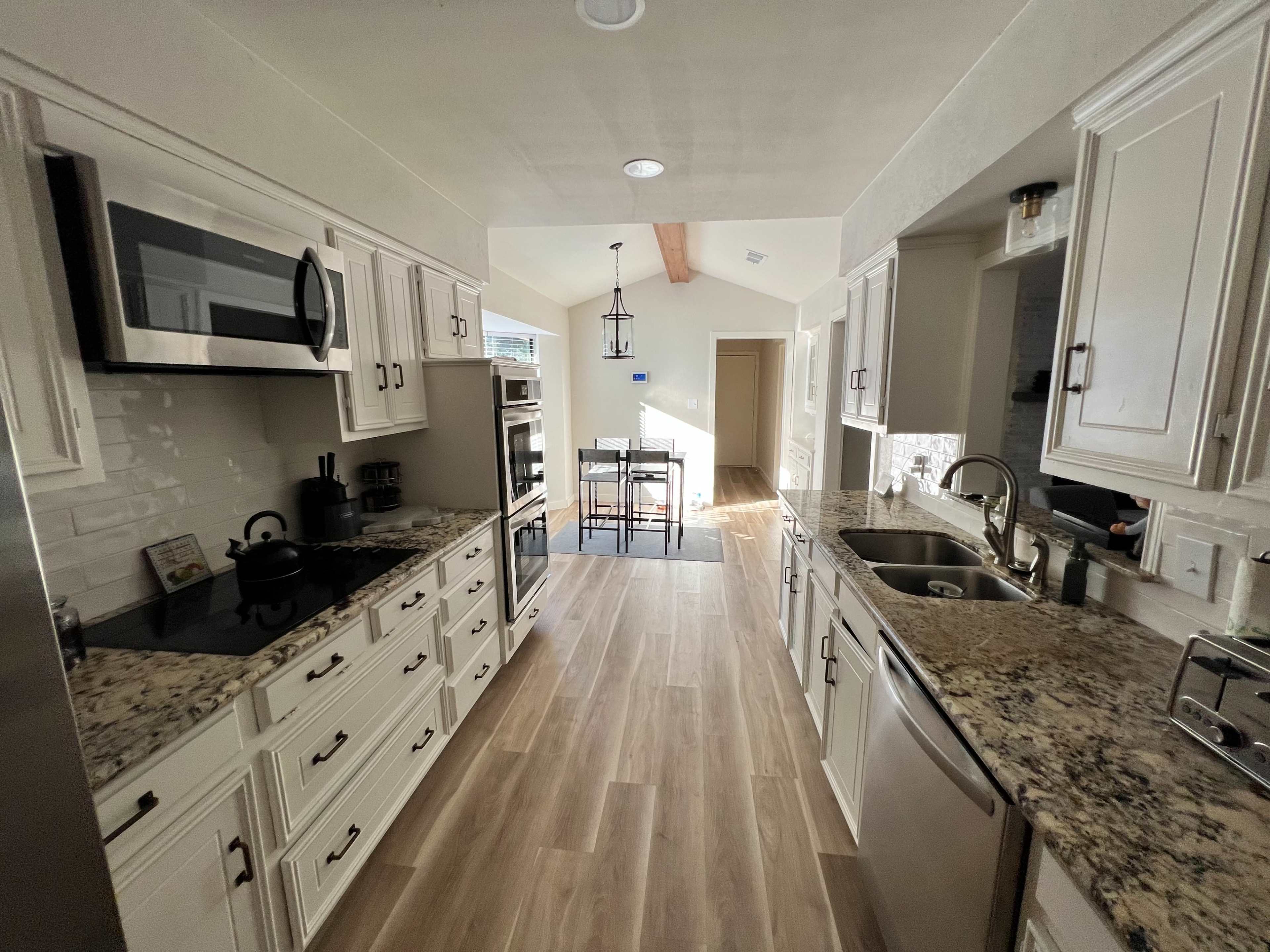 A modern kitchen with granite countertops, stainless steel appliances, and a tile floor, featuring an open layout that leads to a dining area.