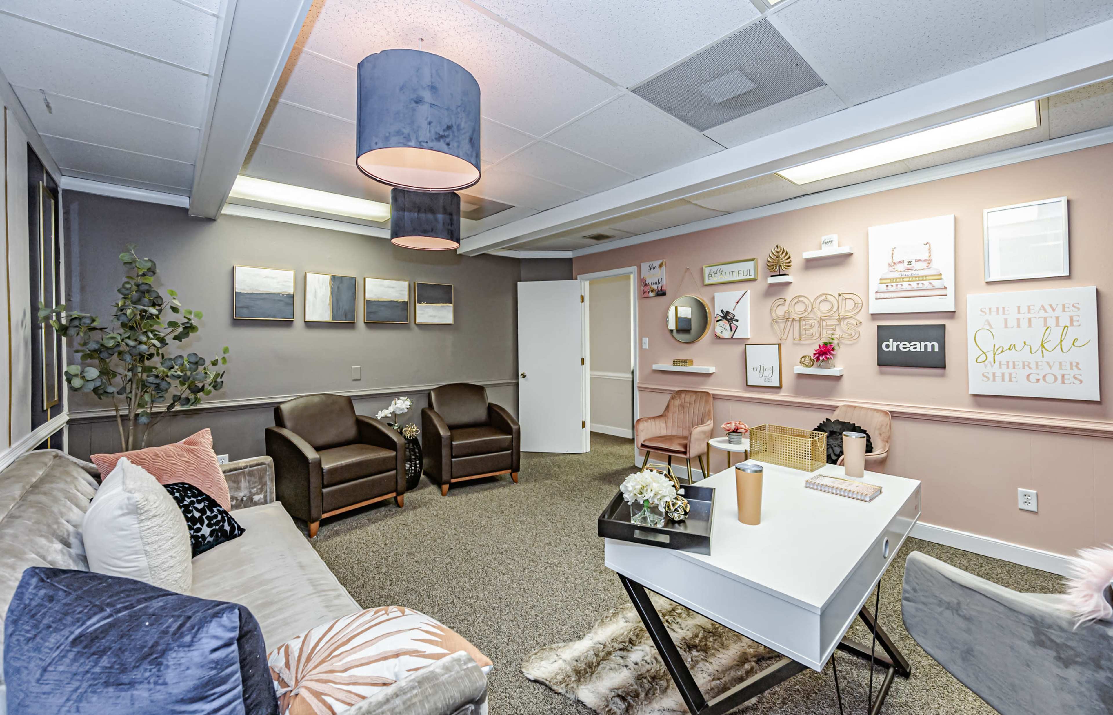 A well-furnished office lounge with a mix of modern seating, decorative wall art, and plants.