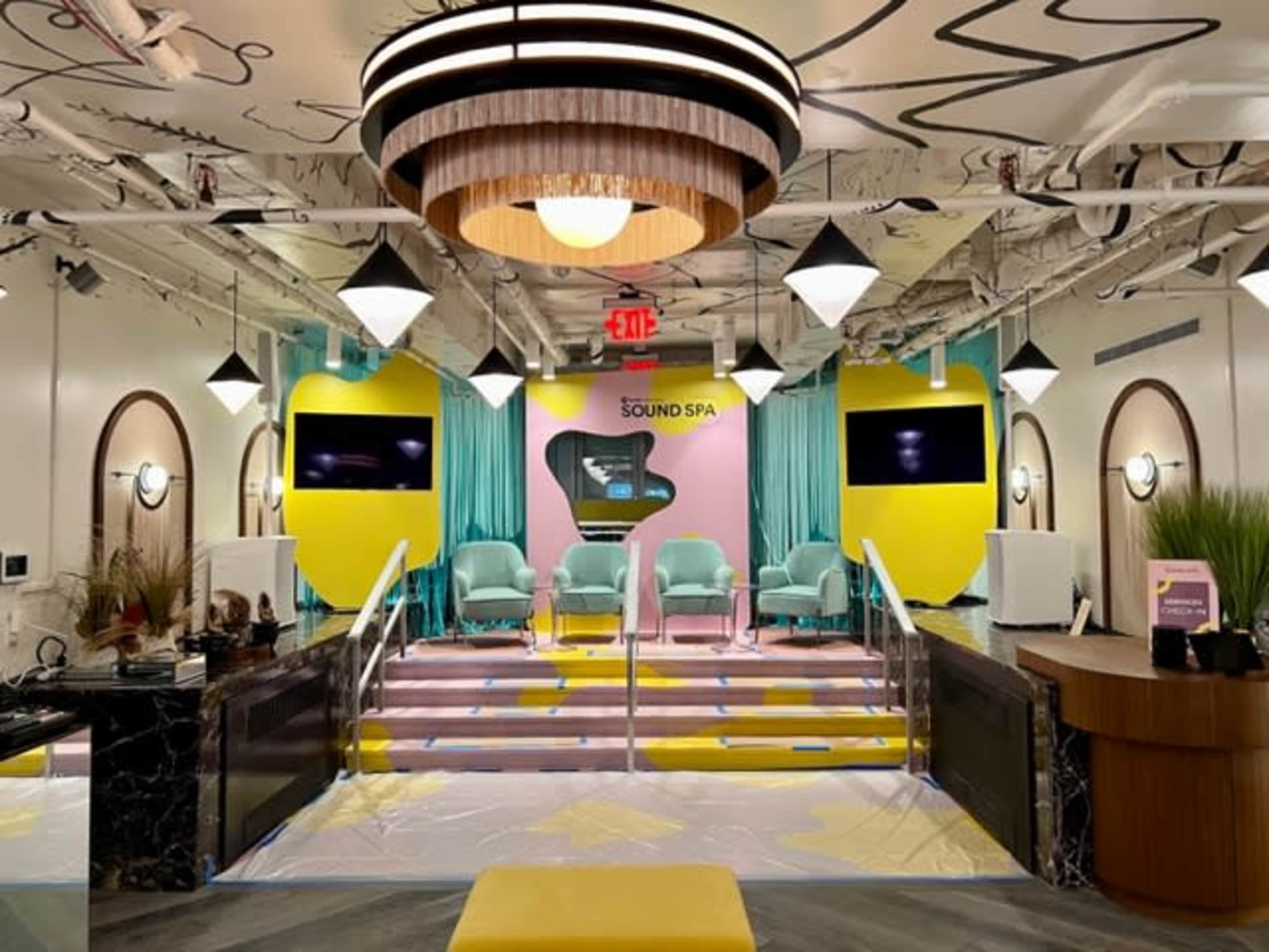A modern spa interior featuring a bright color scheme with green chairs, yellow accents, and a reception area.