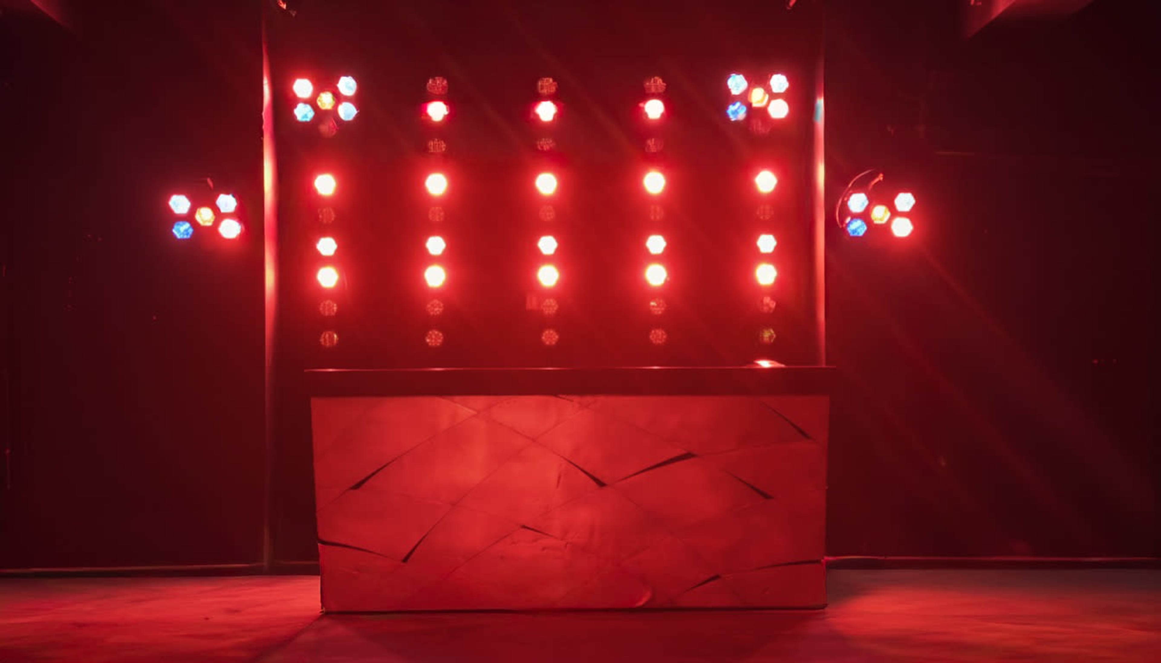 A stage is illuminated with red lights and features a textured backdrop.