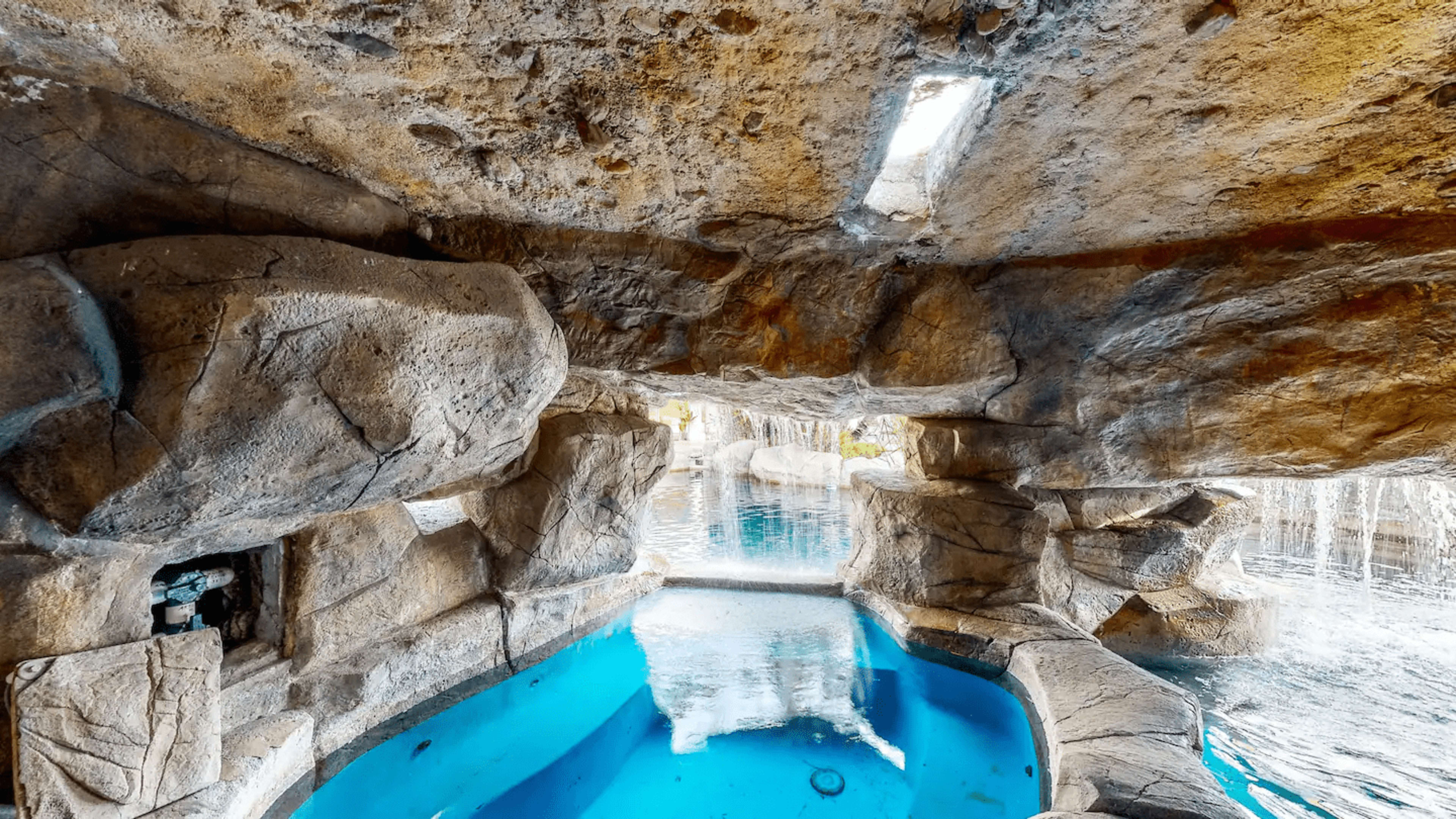 A secluded cave-like pool area with natural rock formation and clear blue water.