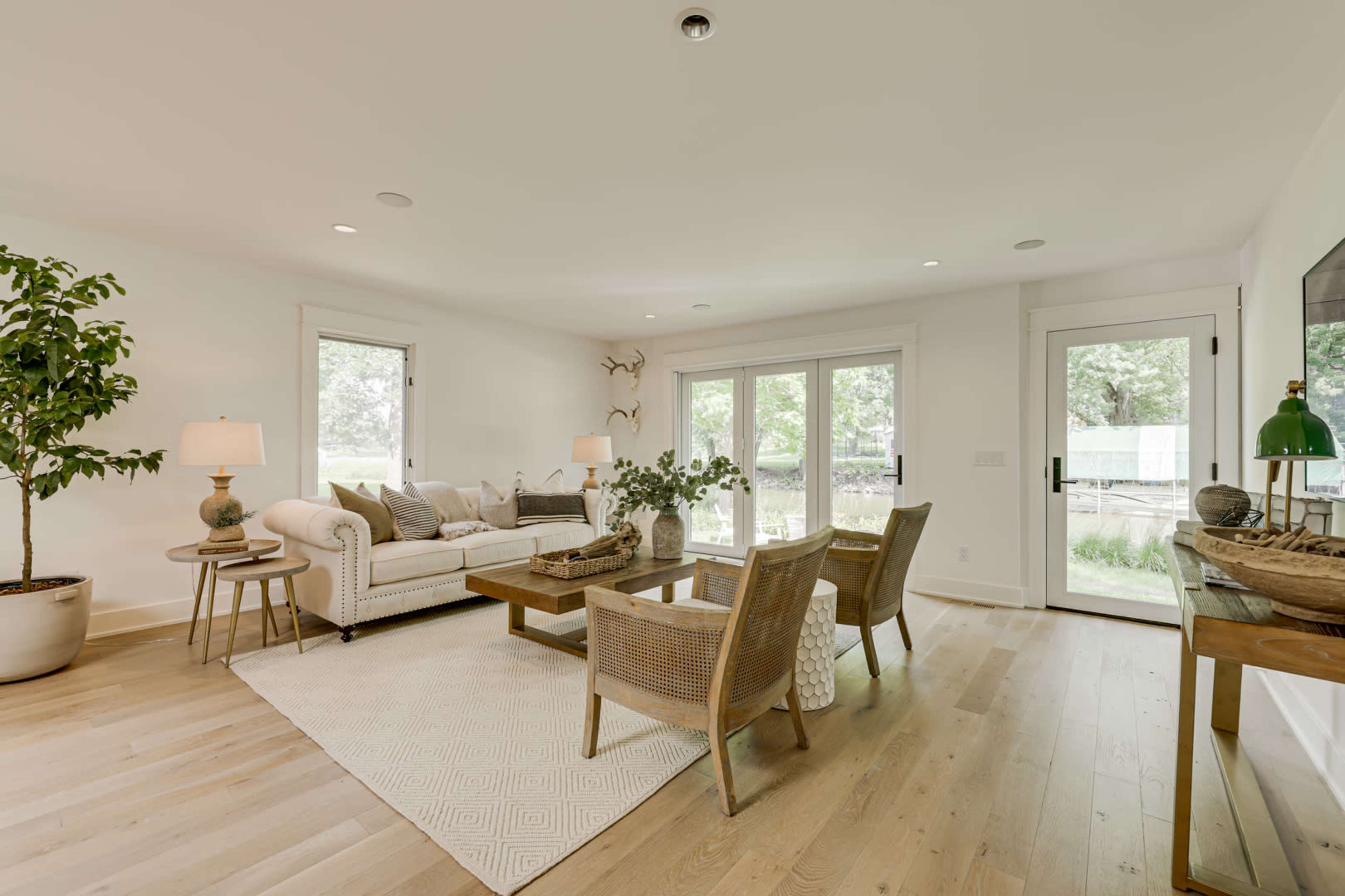 A bright living room featuring a white sofa, wooden coffee table, and sliding glass doors leading to an outdoor space.