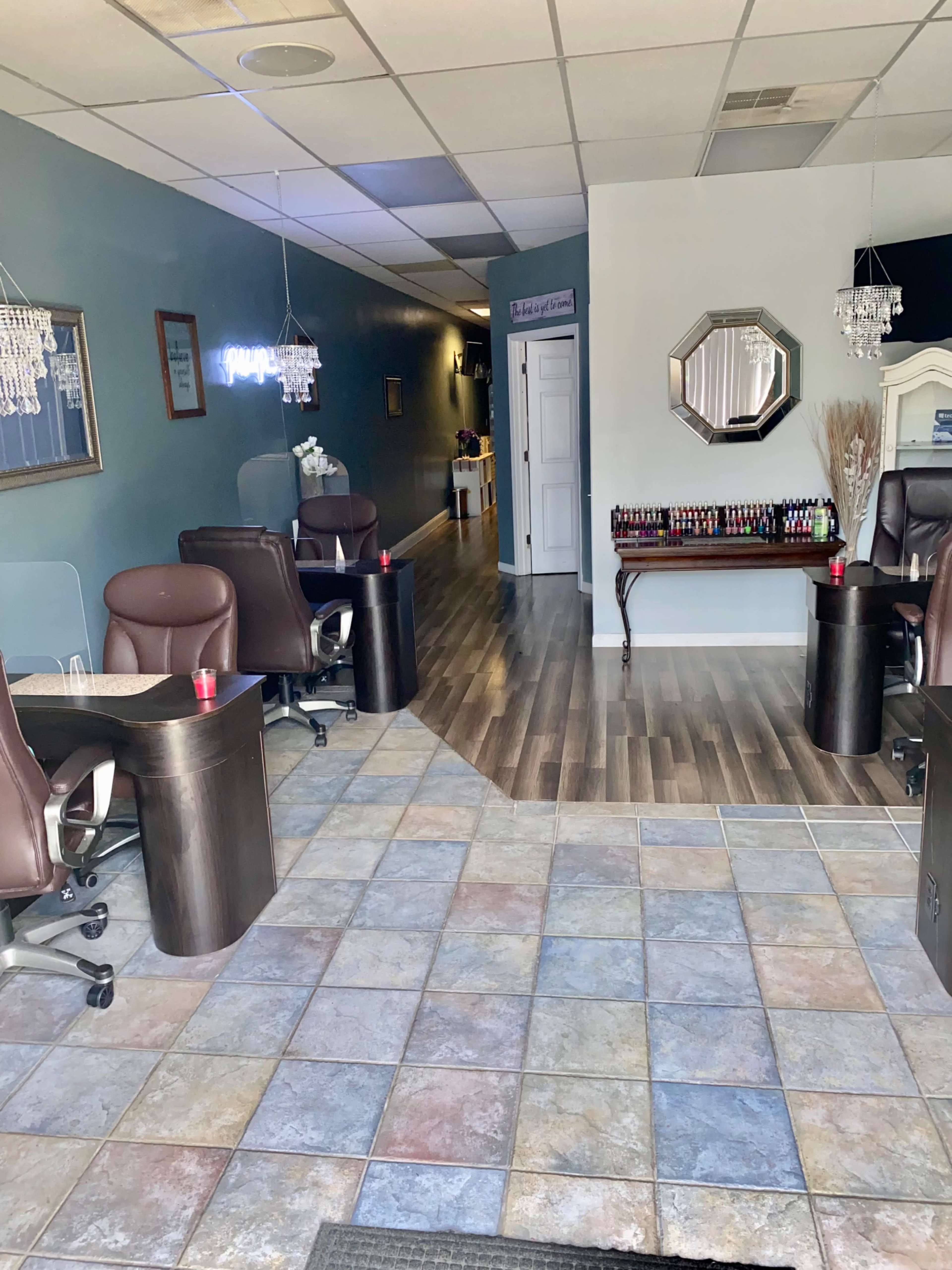 A nail salon interior featuring several manicure stations, a long hallway, and a display of nail polish.