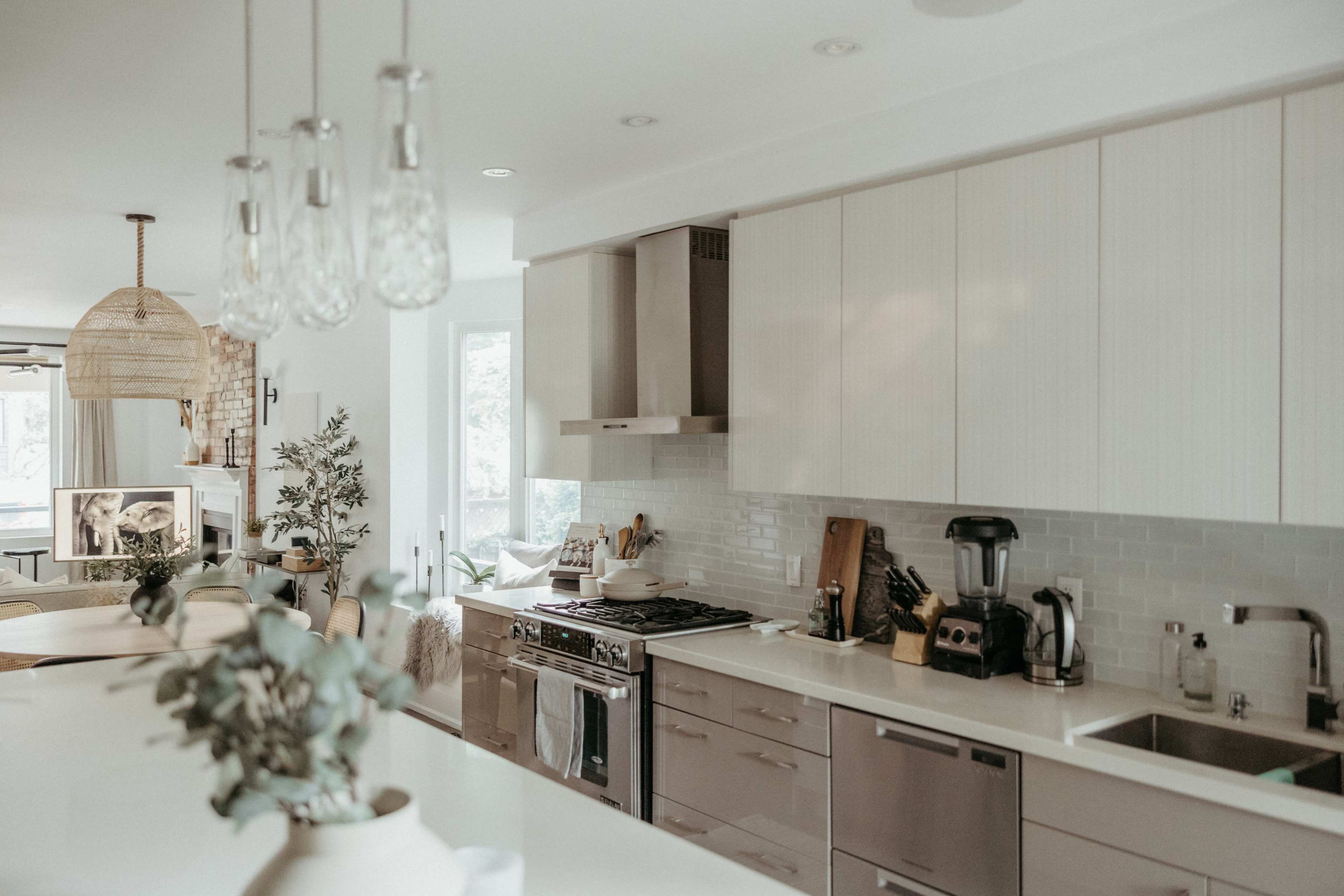 A modern kitchen features light cabinetry, a stainless steel stove, and a central island with seating.