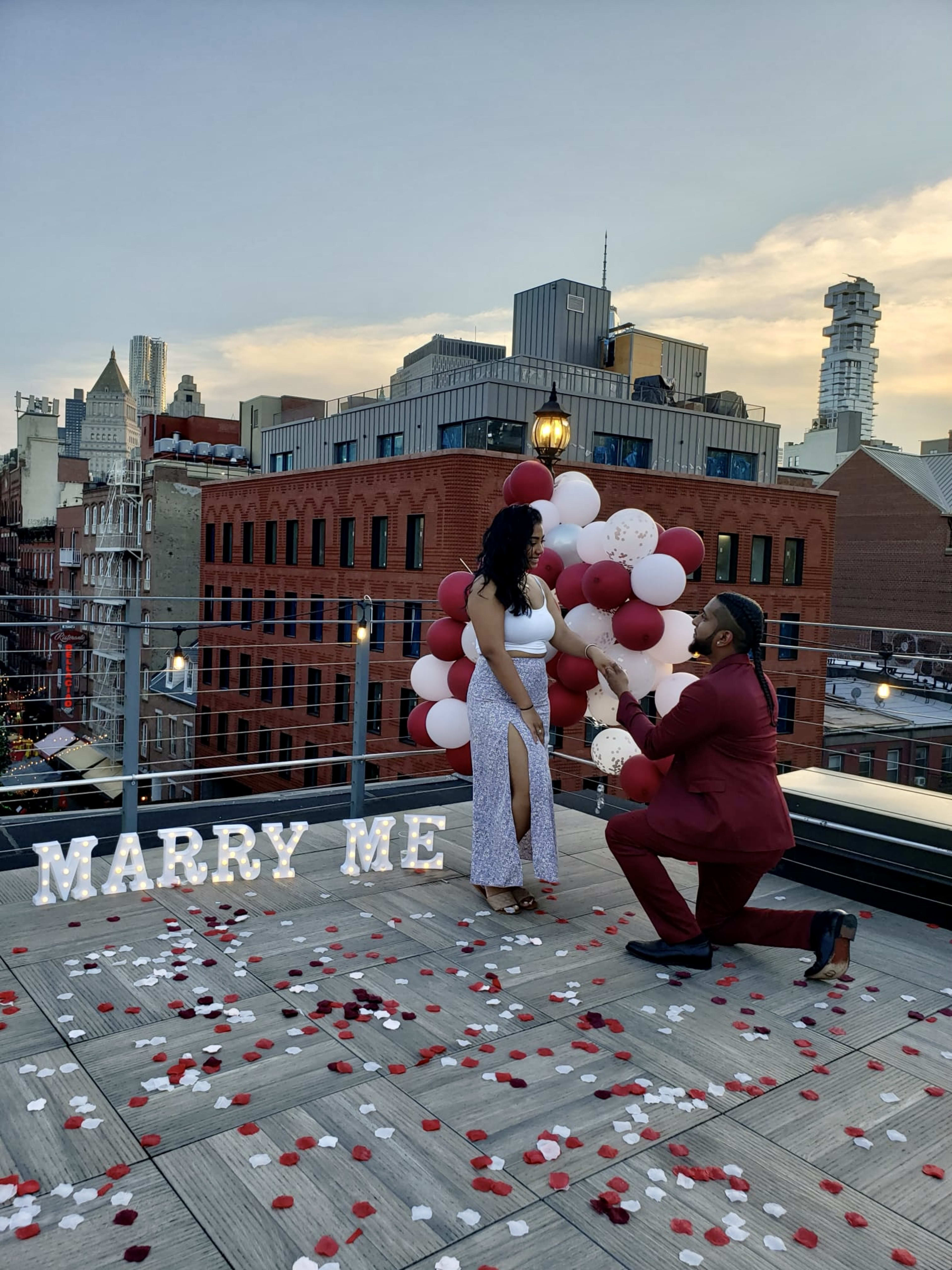 A man propose to a woman on top of a party roof.