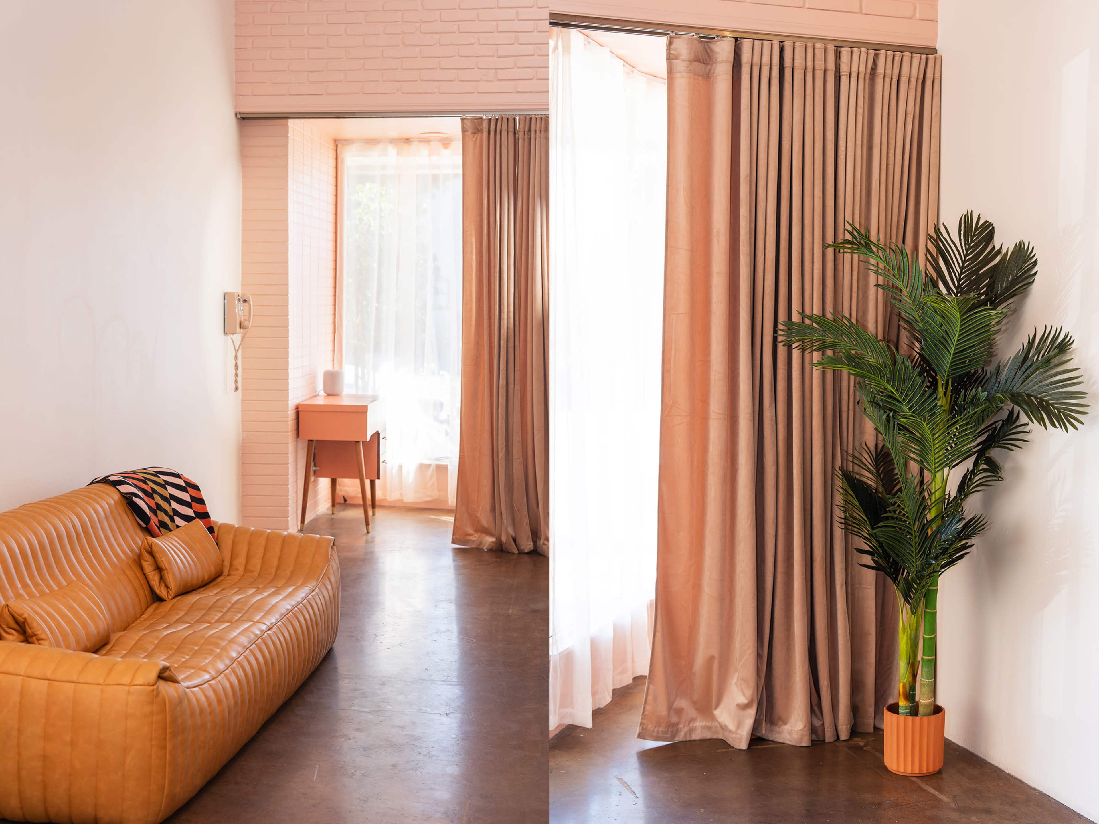 A modern interior features a brown sofa, potted plant, and sheer curtains dividing two adjoining spaces.