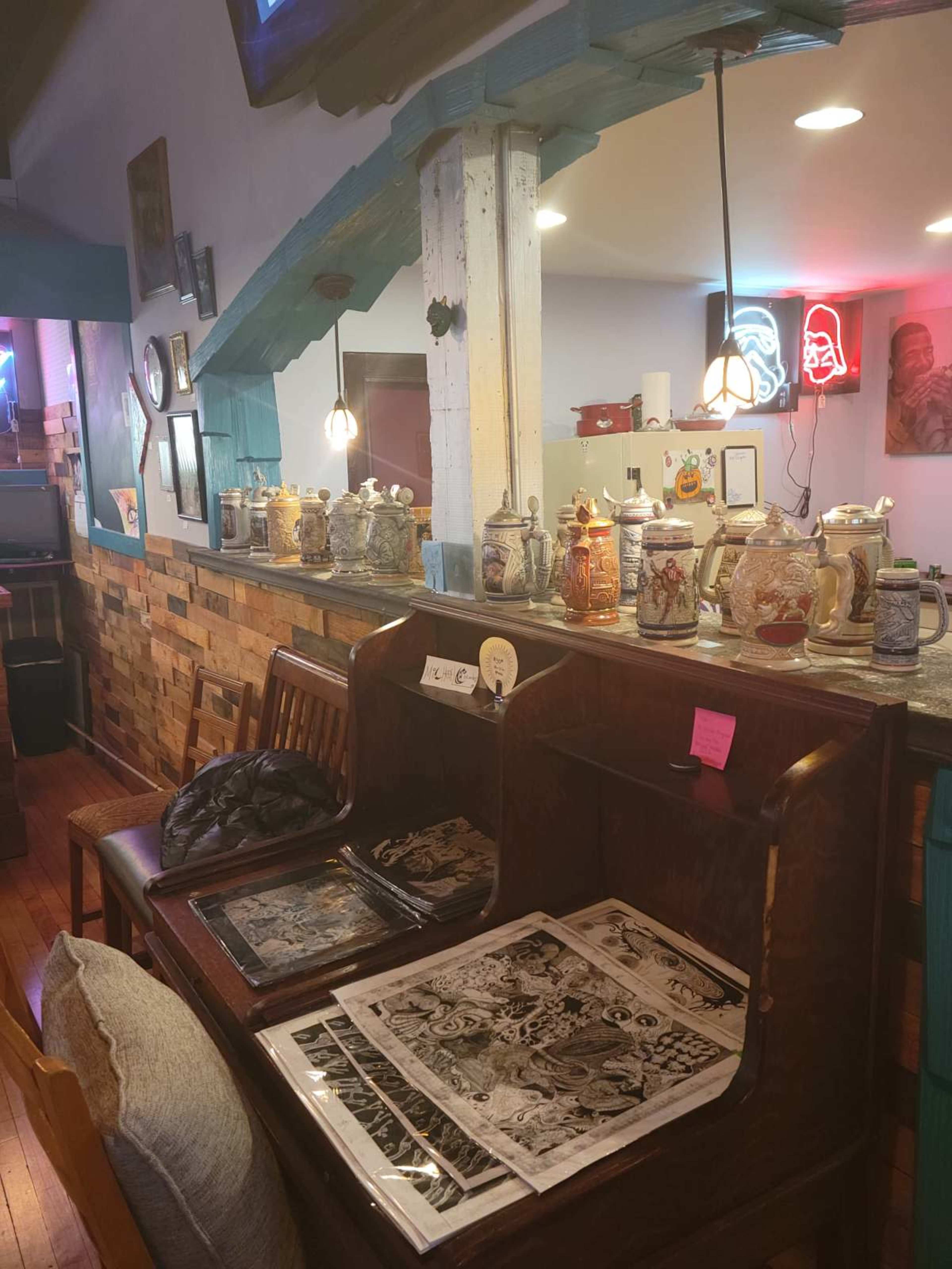 The image shows a cozy interior with wooden furniture, decorative beer steins displayed on shelves, and illuminated signs creating a warm atmosphere.