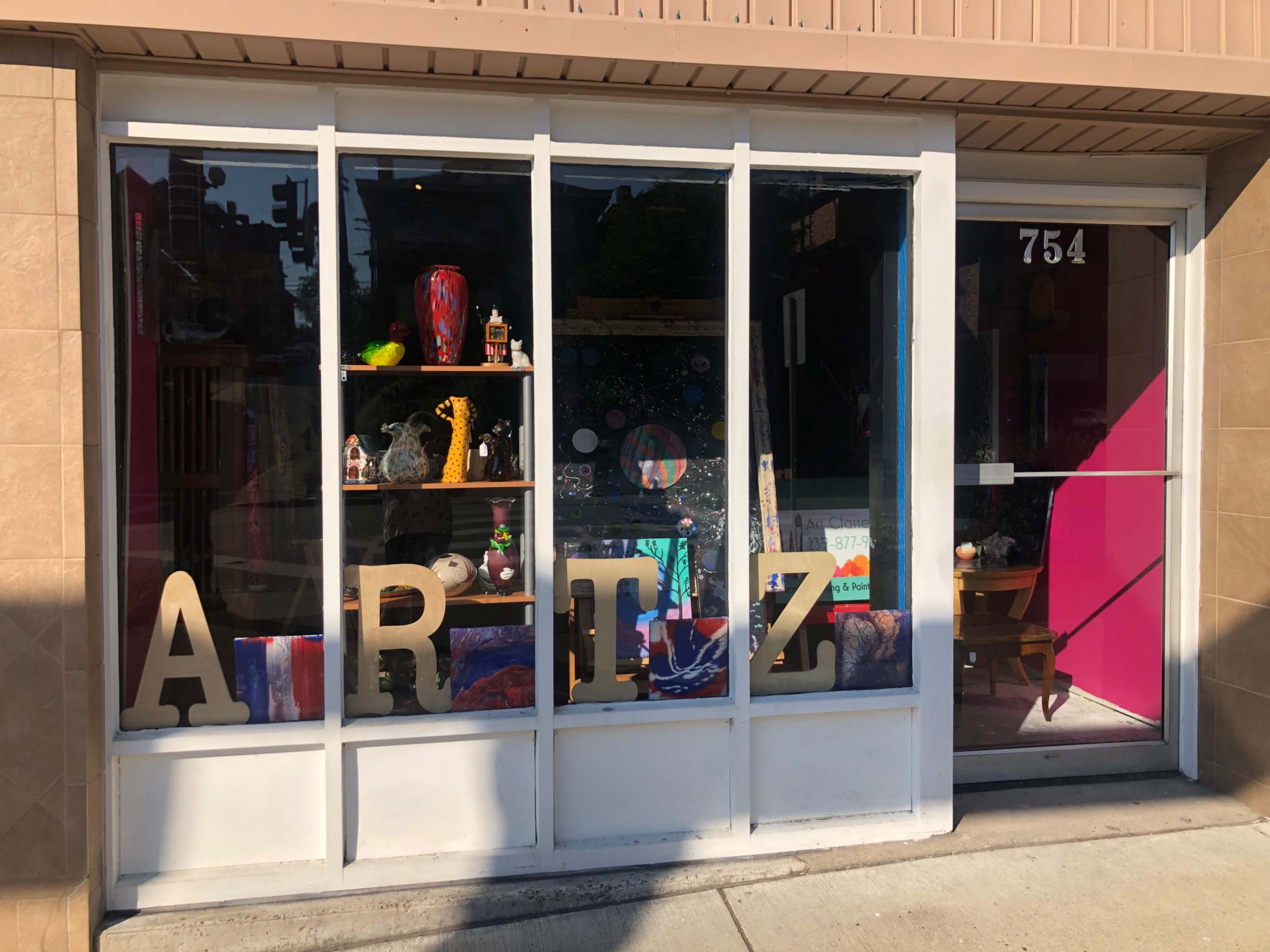A shop window displays the word "ARTZ" in large letters, surrounded by various decorative items and artwork.