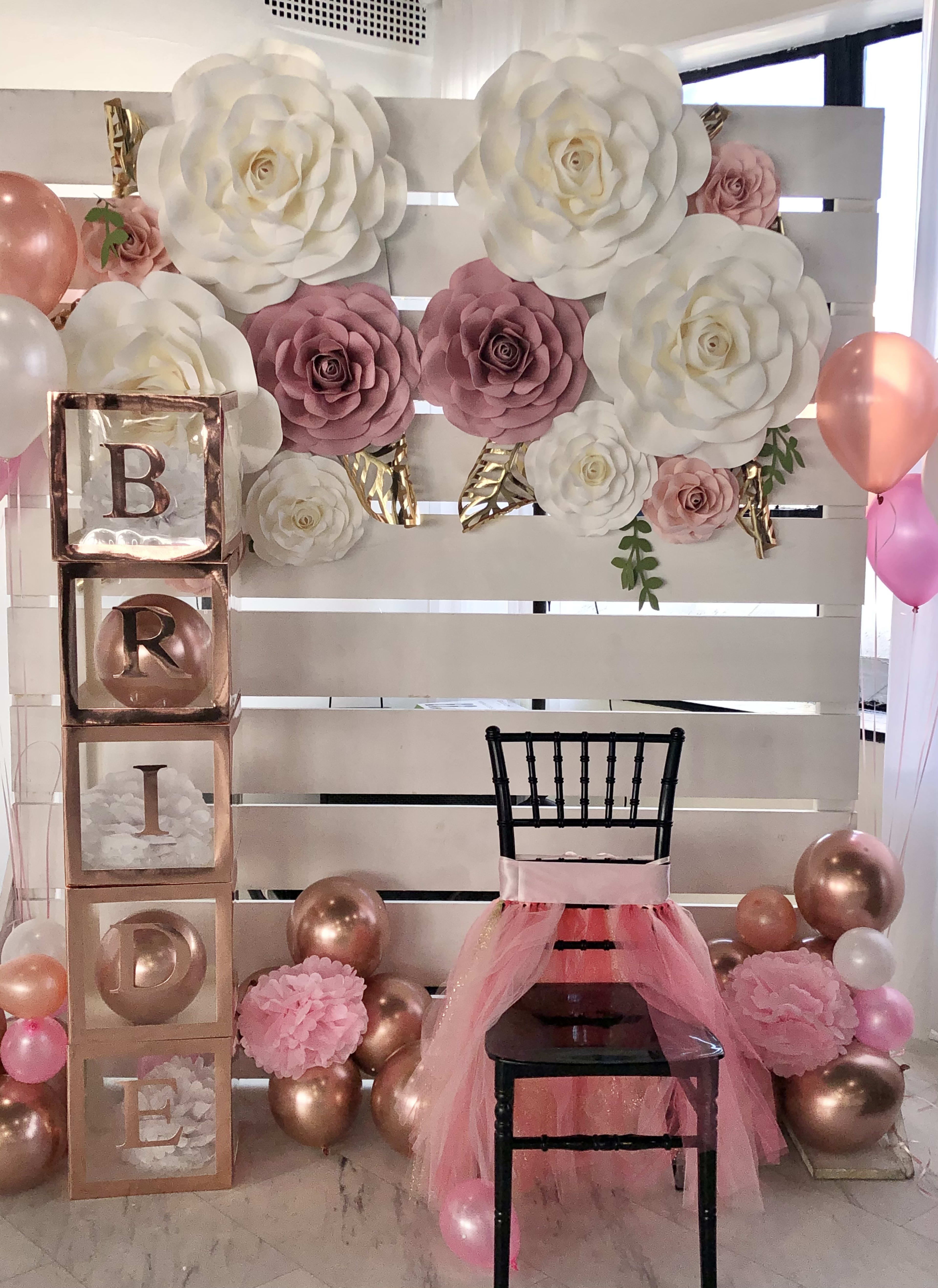 Ein mit rosa und weißen Luftballons geschmückter Gartentisch und ein Stuhl für eine Brautparty.
