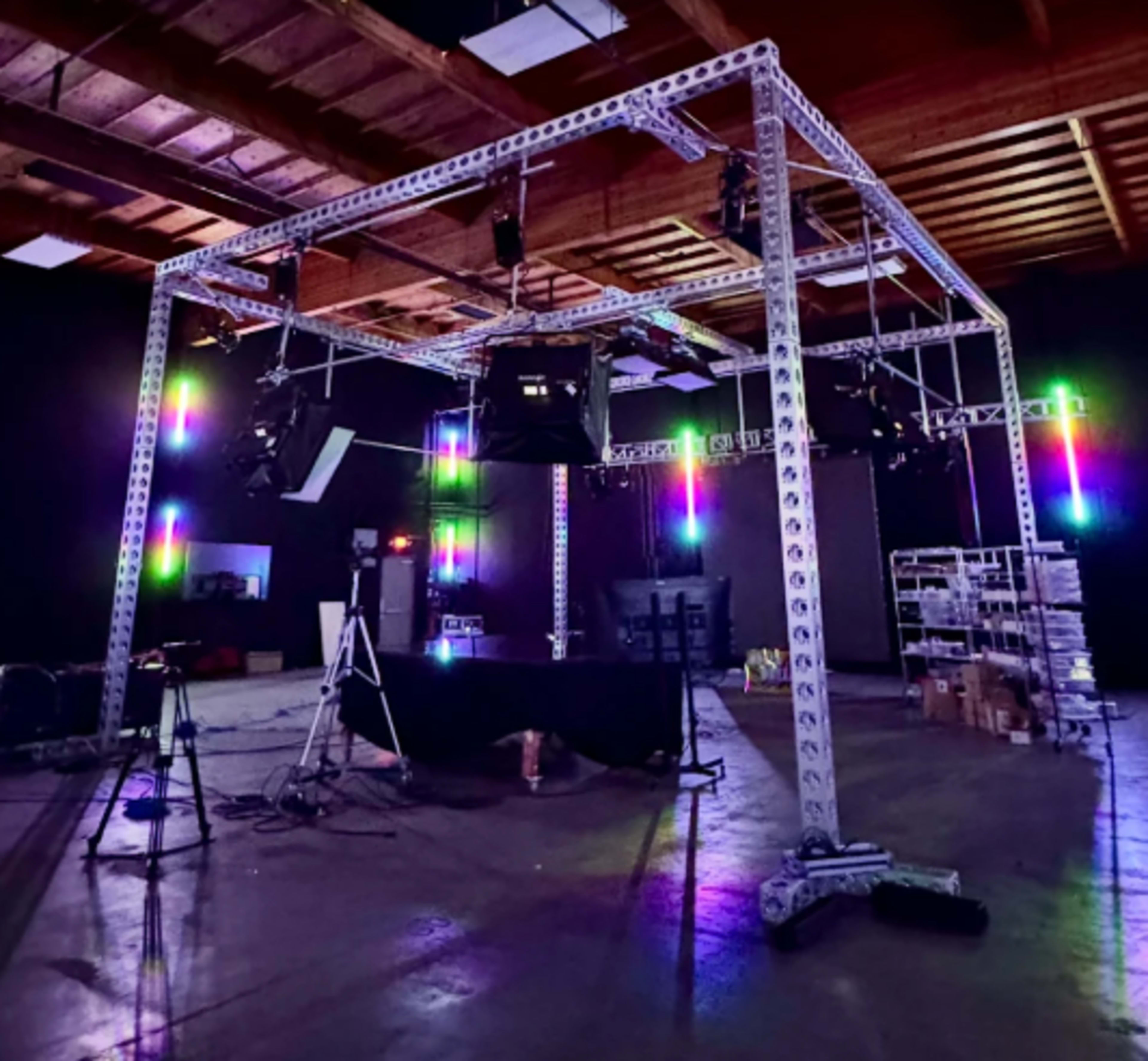 A metal frame structure with lights and equipment is set up in a spacious studio or warehouse environment.