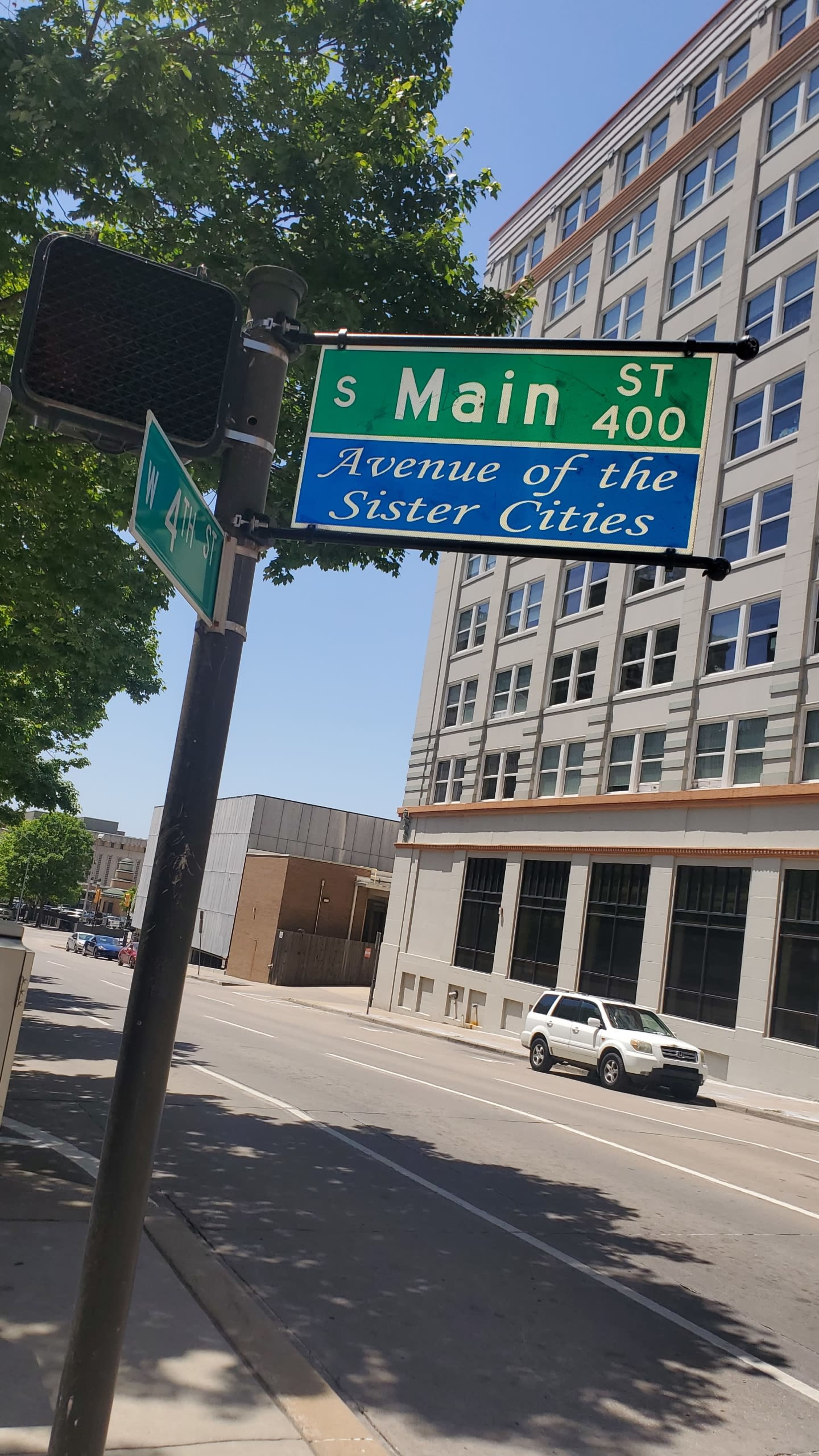 A street sign at the intersection of South Main Street and West 4th Street displays the designation "Avenue of the Sister Cities."