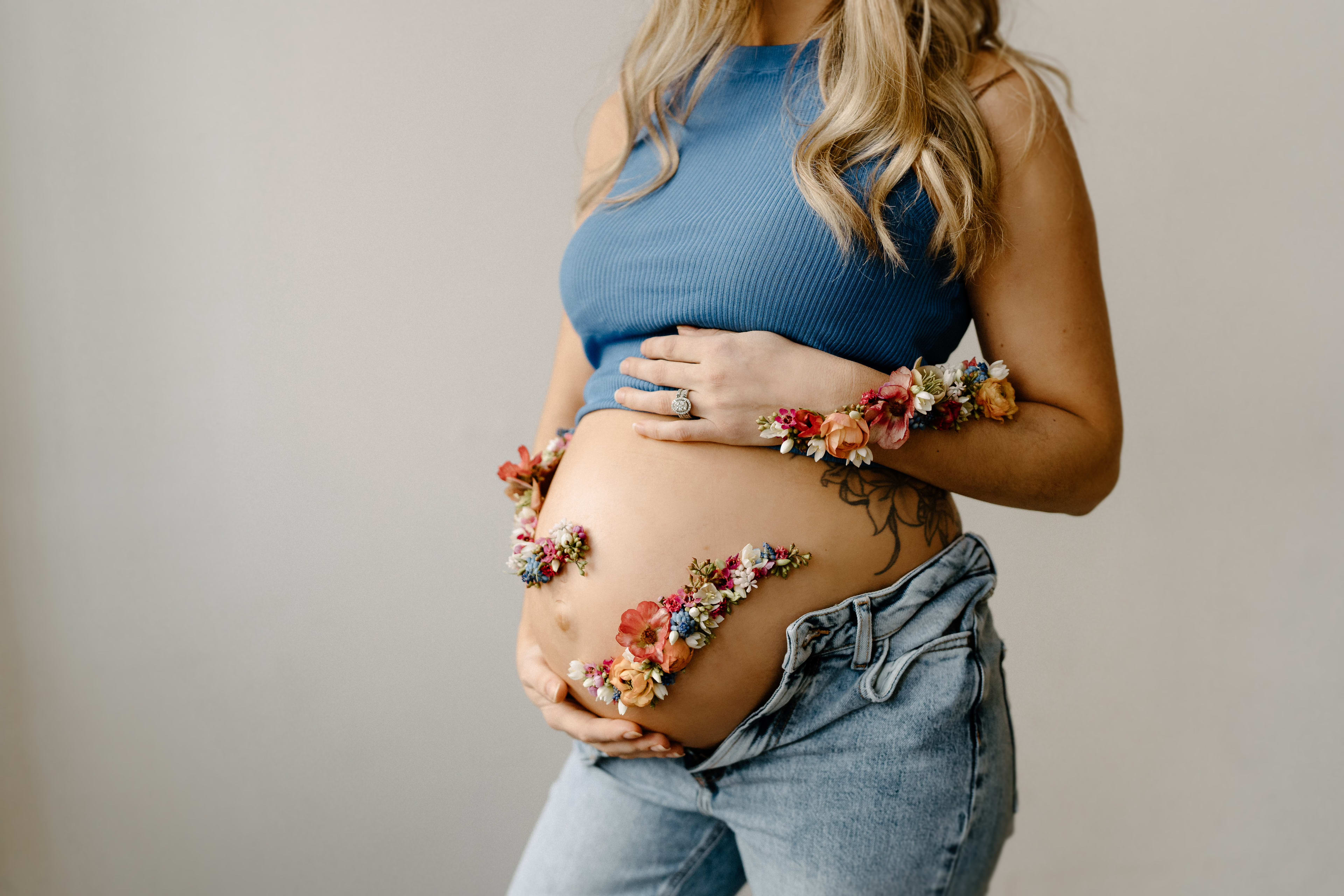 Ein Frühlings-Schwangerschaftsfotoshooting mit einer schwangeren Frau in einem blauen Top und Jeans.