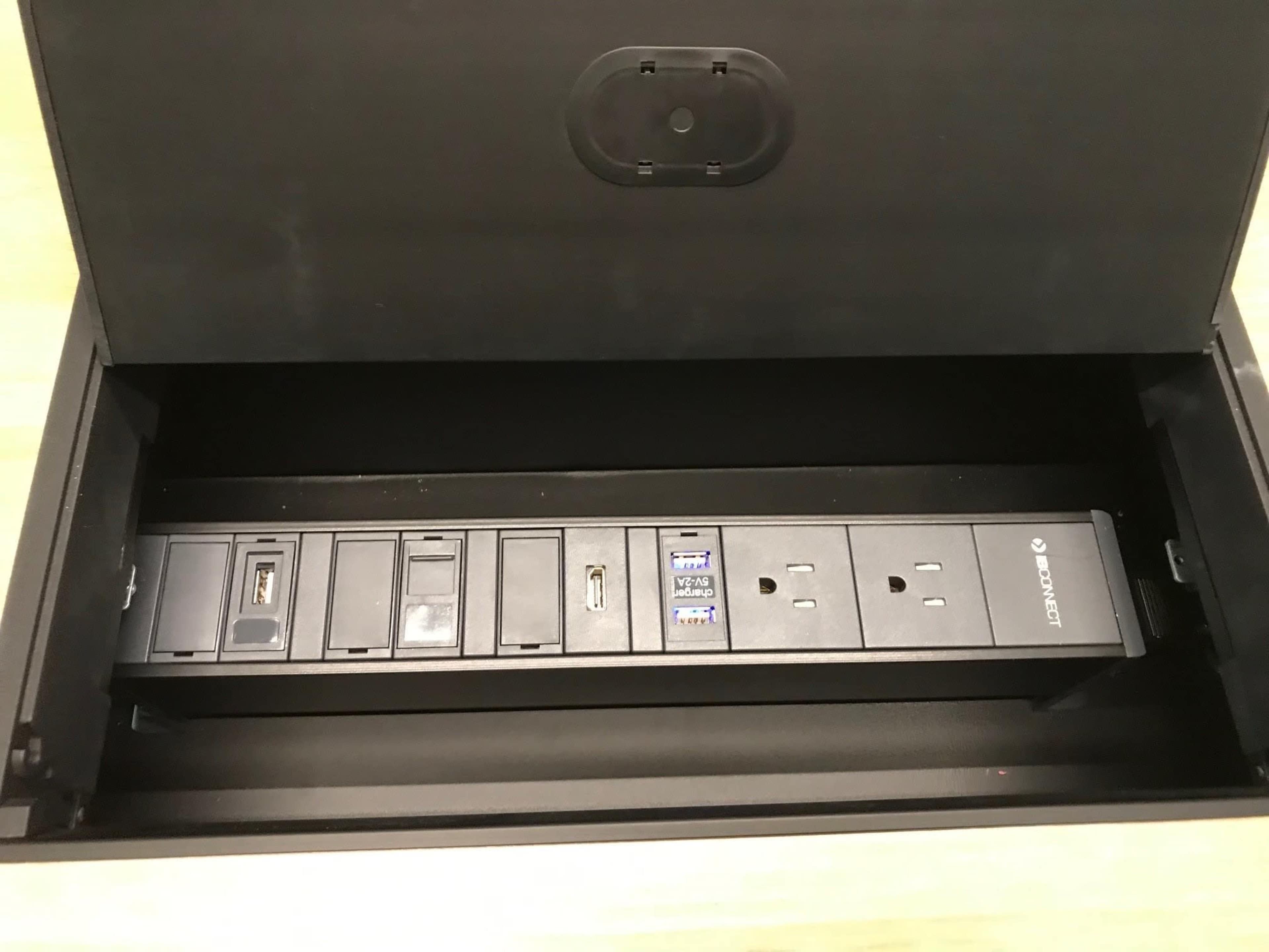 A black power and USB hub with multiple outlets and ports, housed in a rectangular box with a lid open.