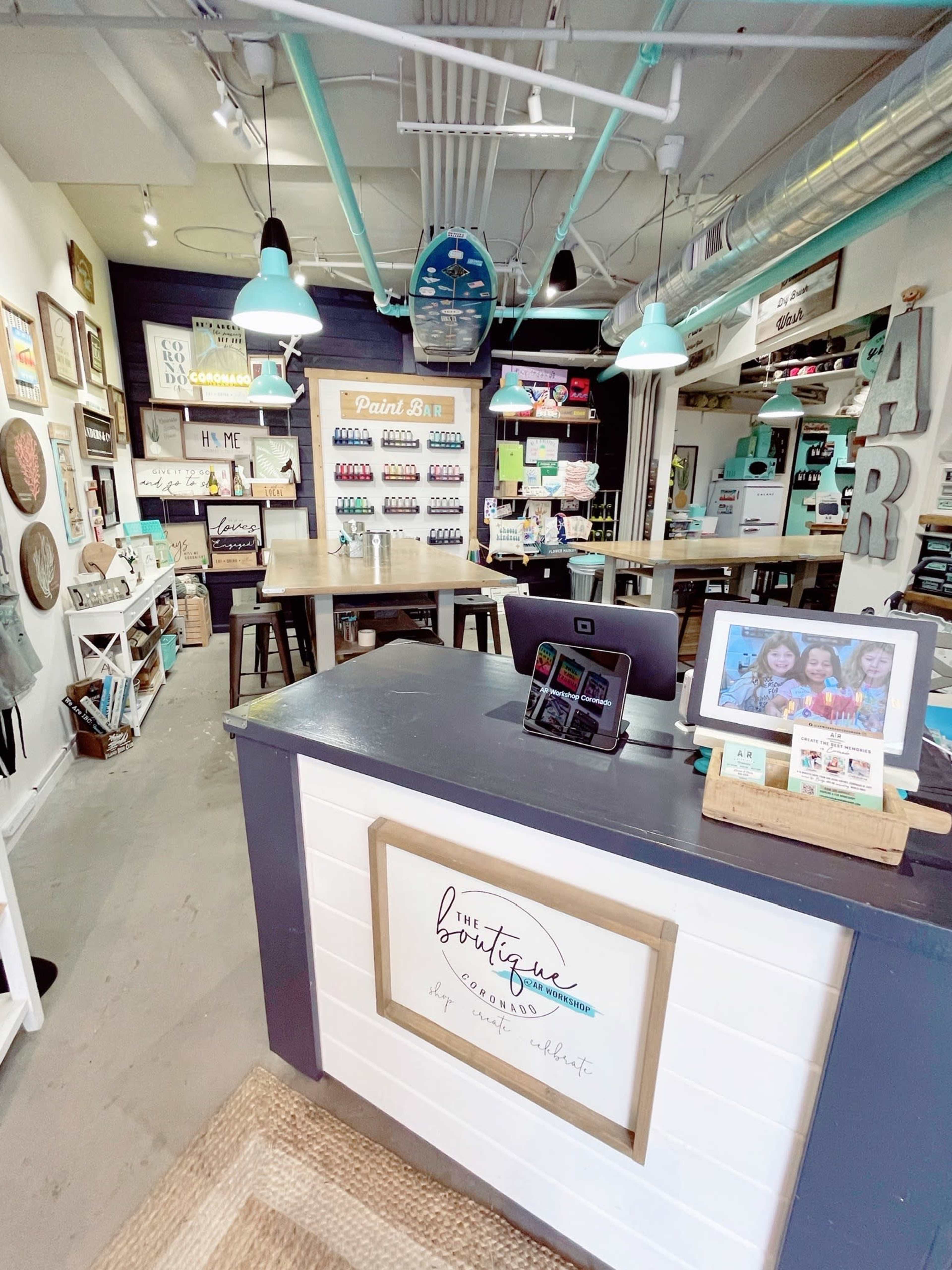 A colorful craft boutique featuring a service desk at the front, shelves of paint supplies, and various art pieces on the walls.