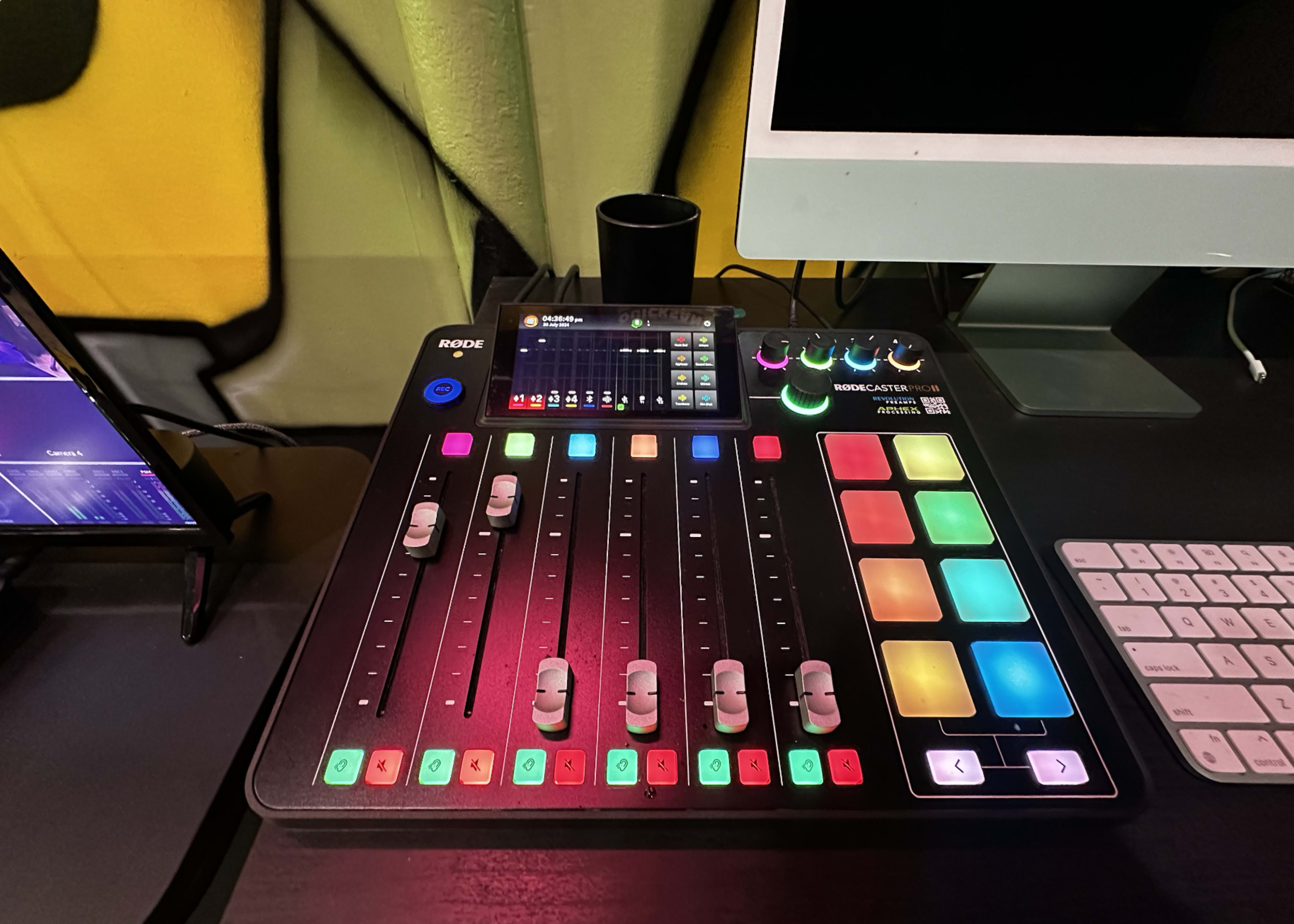 A Rode Rodecaster Pro audio production mixer placed on a desk alongside a computer and a keyboard.