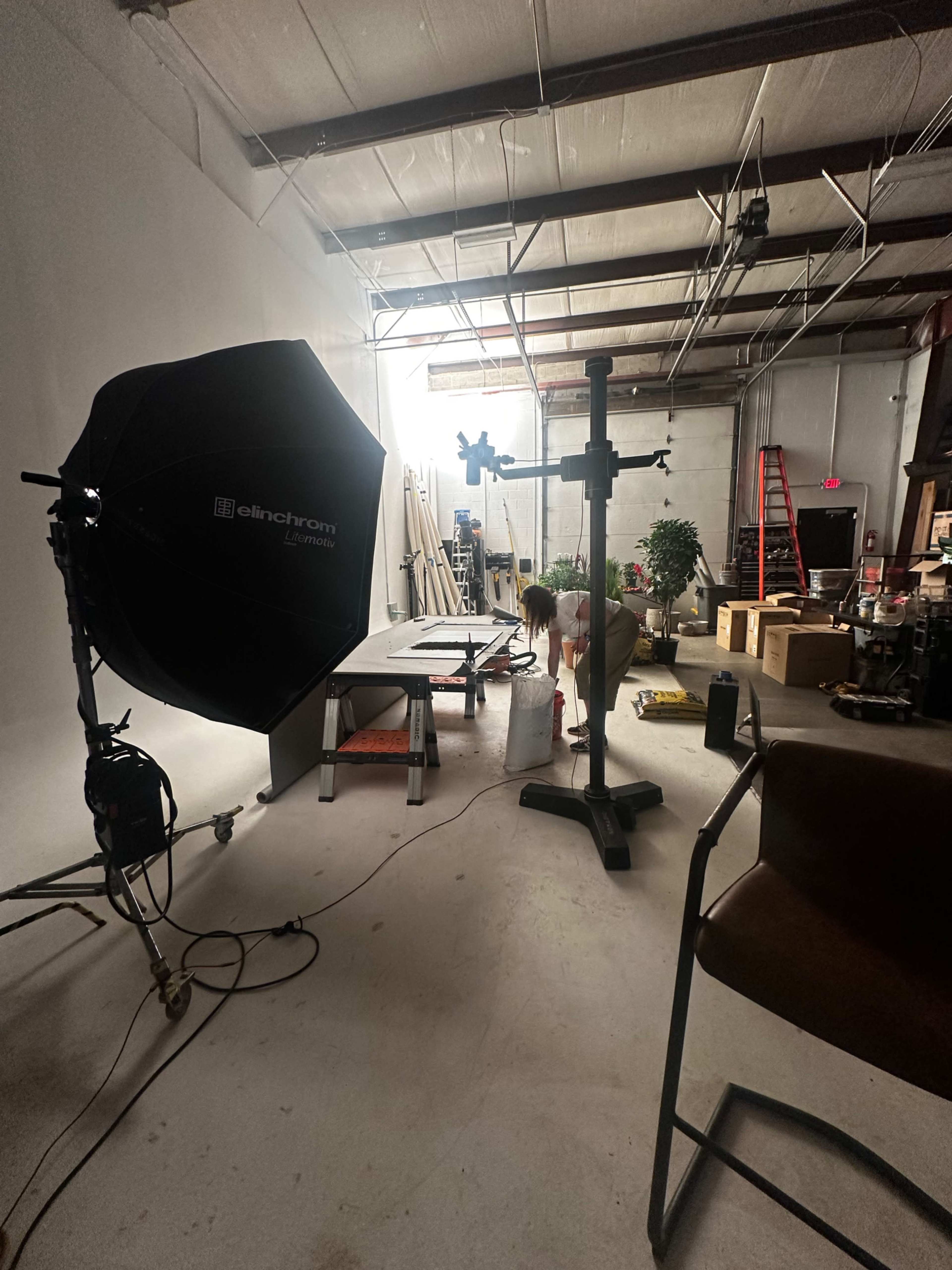 A person is working on a photography set in a spacious studio filled with equipment and props.