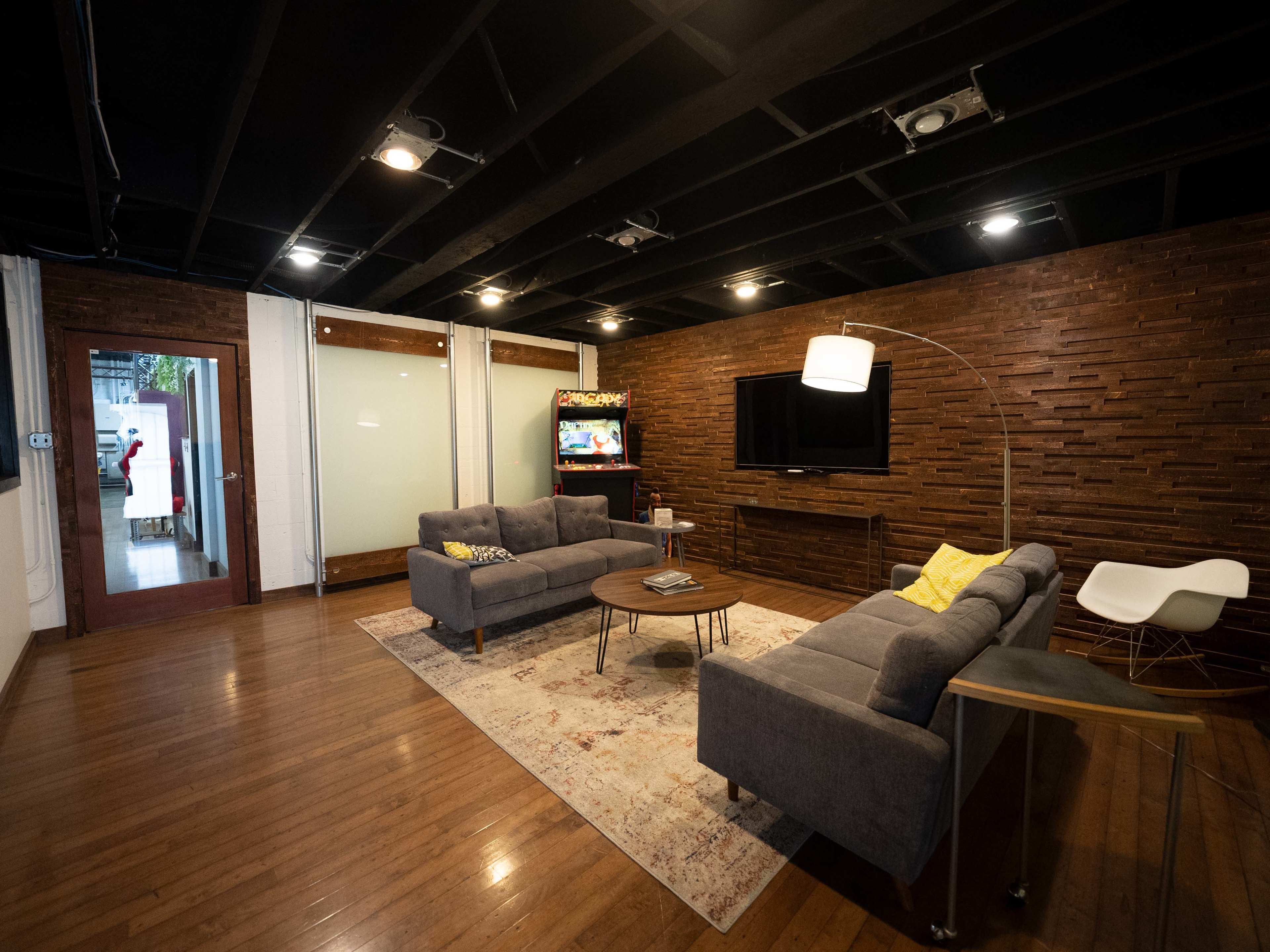 A modern living room with two gray sofas, a coffee table, and a television mounted on a brick accent wall.