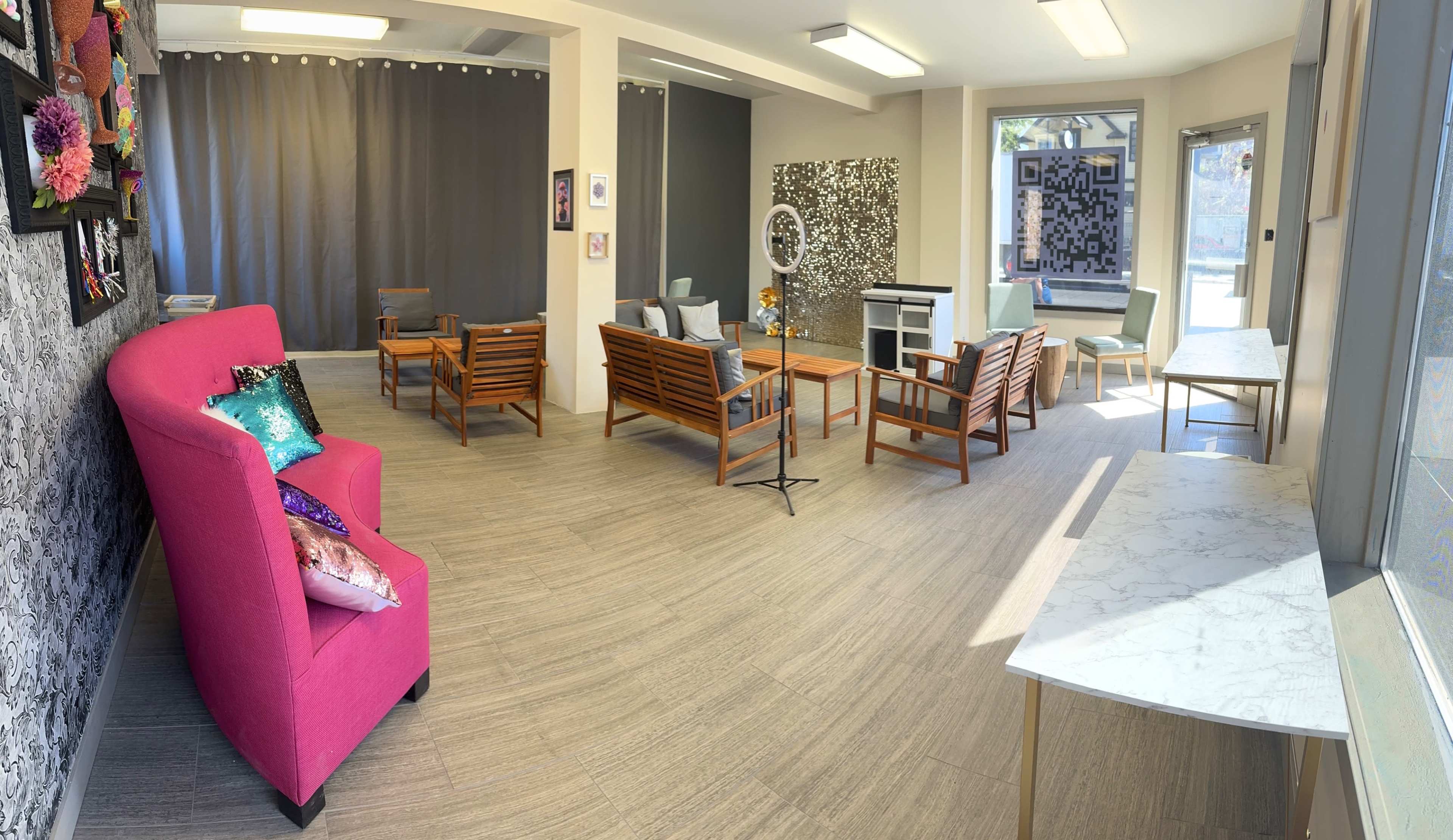 A well-lit, modern room with wooden seating, a pink armchair, and decorative wall art.