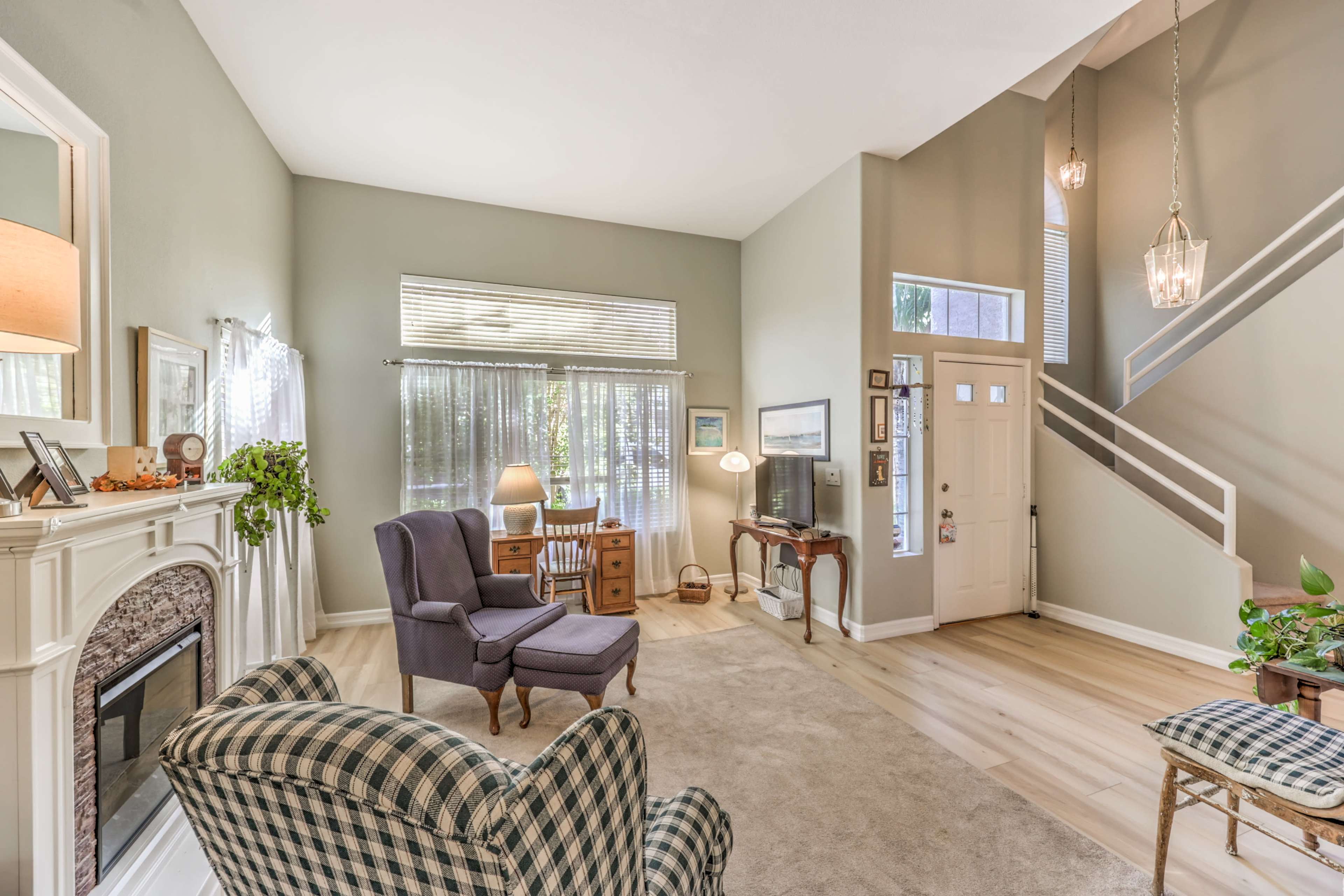 A spacious living room with a cozy seating area, a fireplace, and a staircase leading to an upper level.