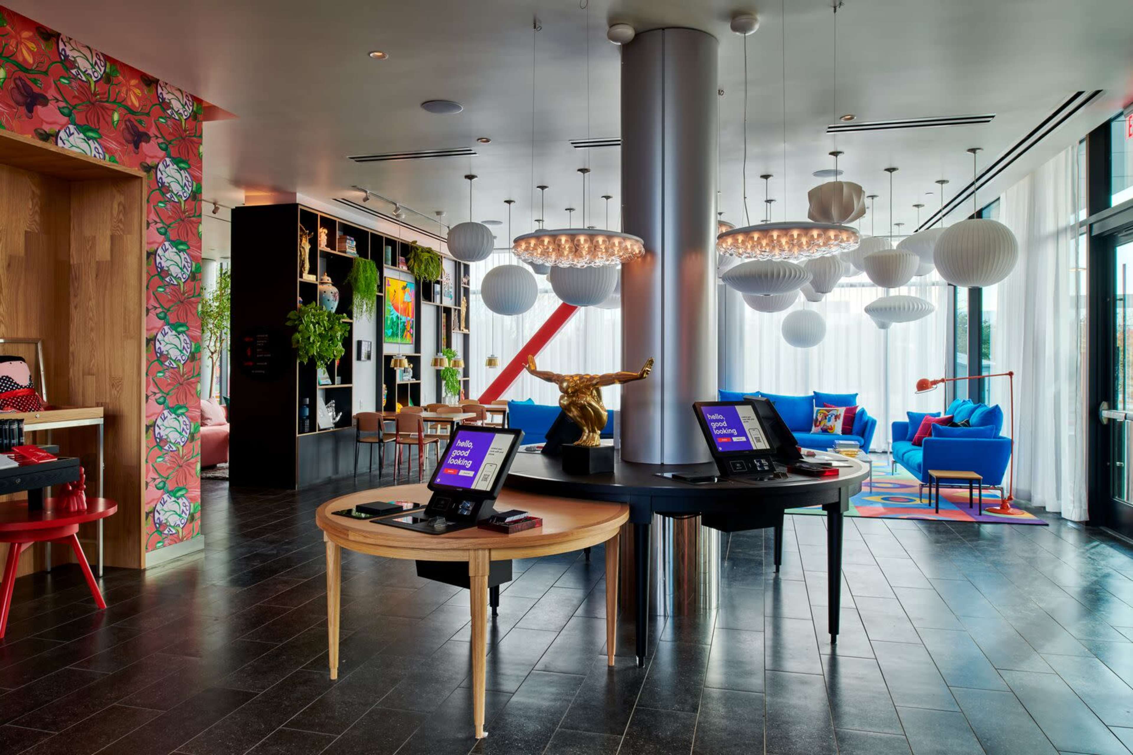 A modern hotel lobby with colorful decor, featuring a central check-in desk, vibrant furniture, and decorative lighting.