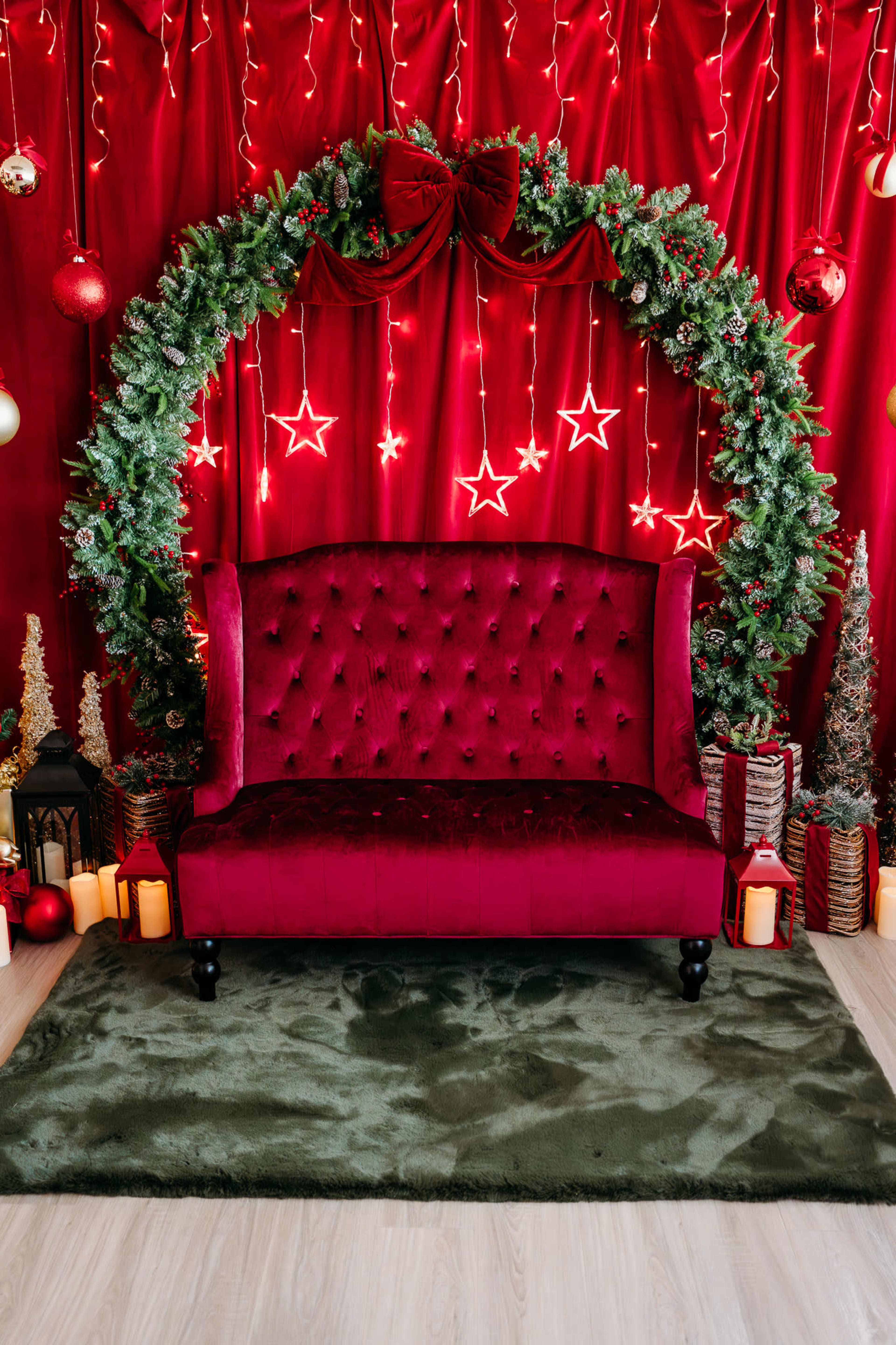 The image features a red velvet sofa in front of a festive backdrop with twinkling lights, a decorative wreath, and various holiday ornaments.