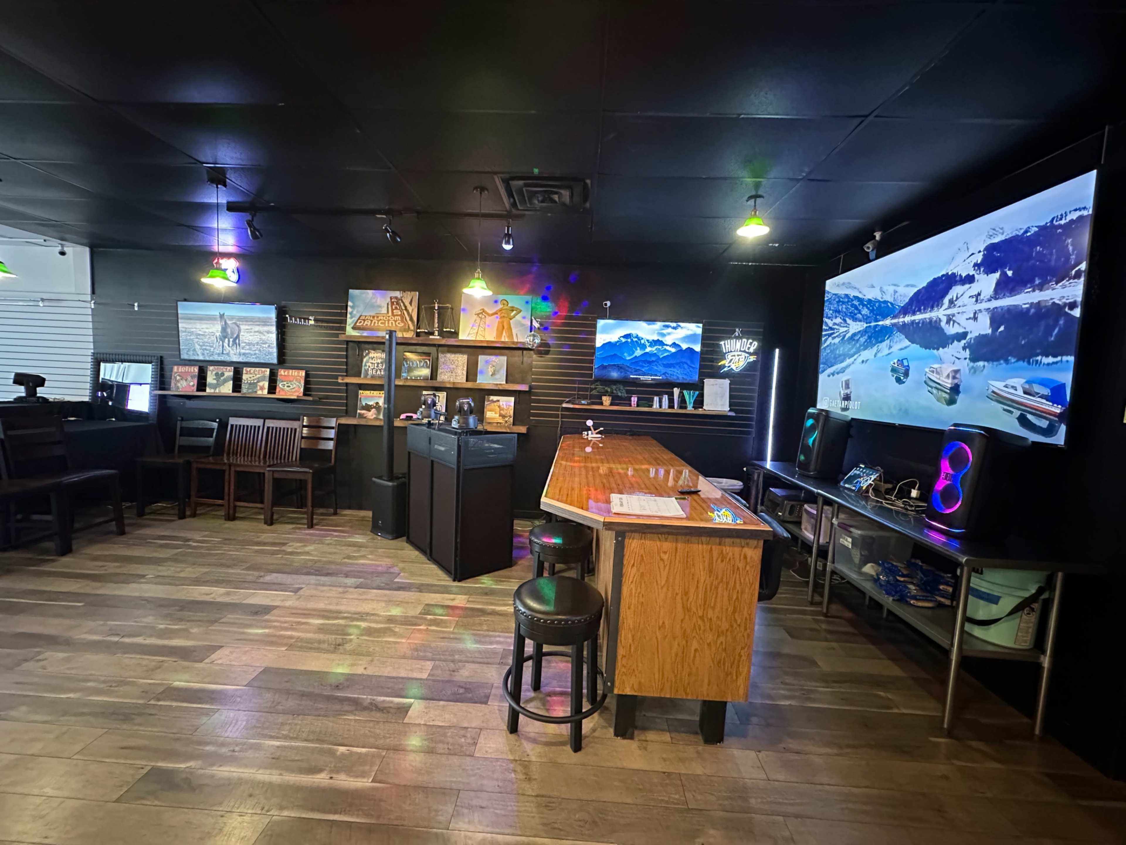 The image showcases a modern entertainment room with a bar area, seating, and multiple screens displaying scenic landscapes.