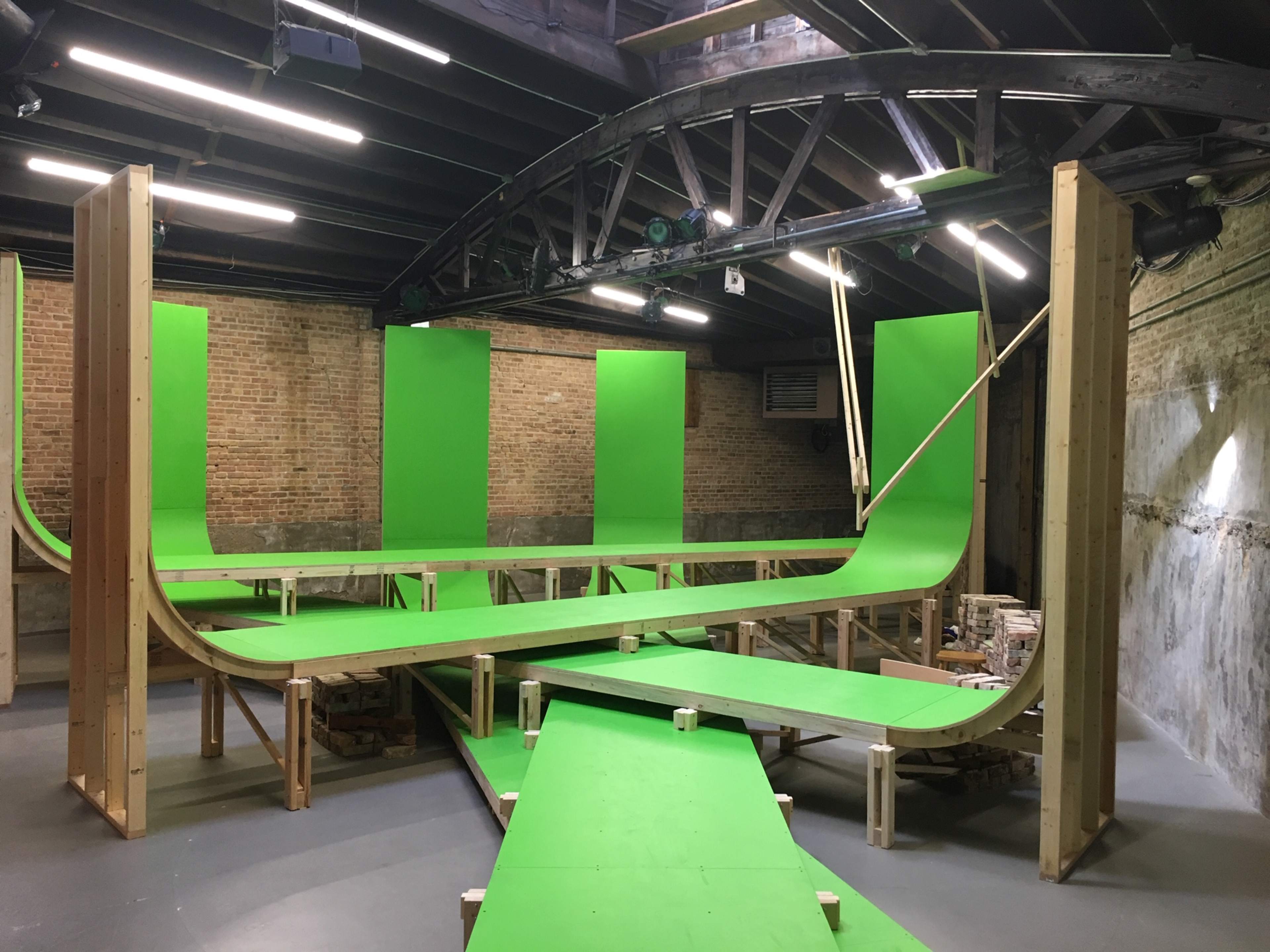 A large indoor space with wooden structures and green ramps arranged in a curved layout.