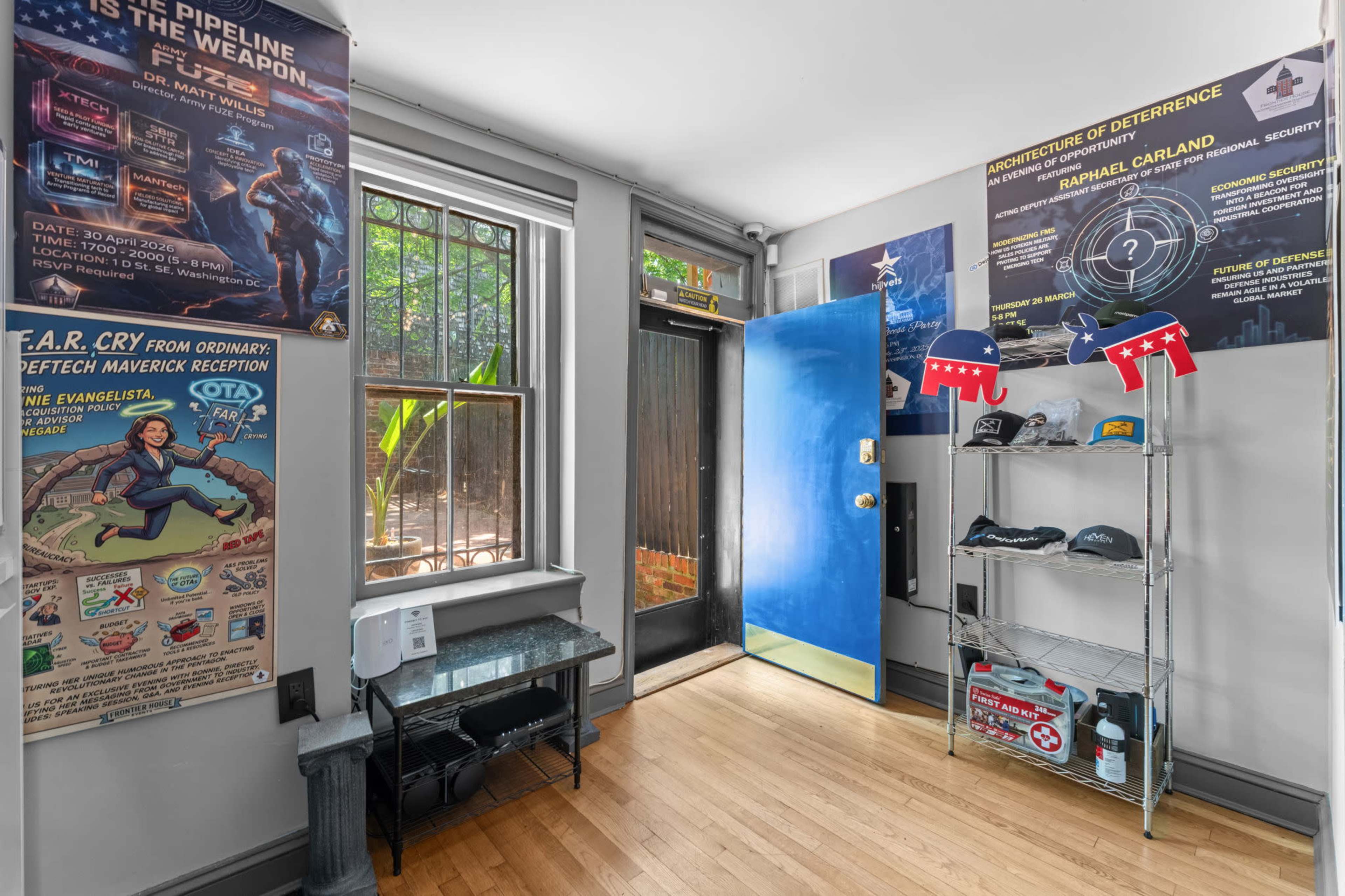 The image shows a brightly lit entrance area with posters on the walls, a blue door, and a metal shelf displaying various items near the door.
