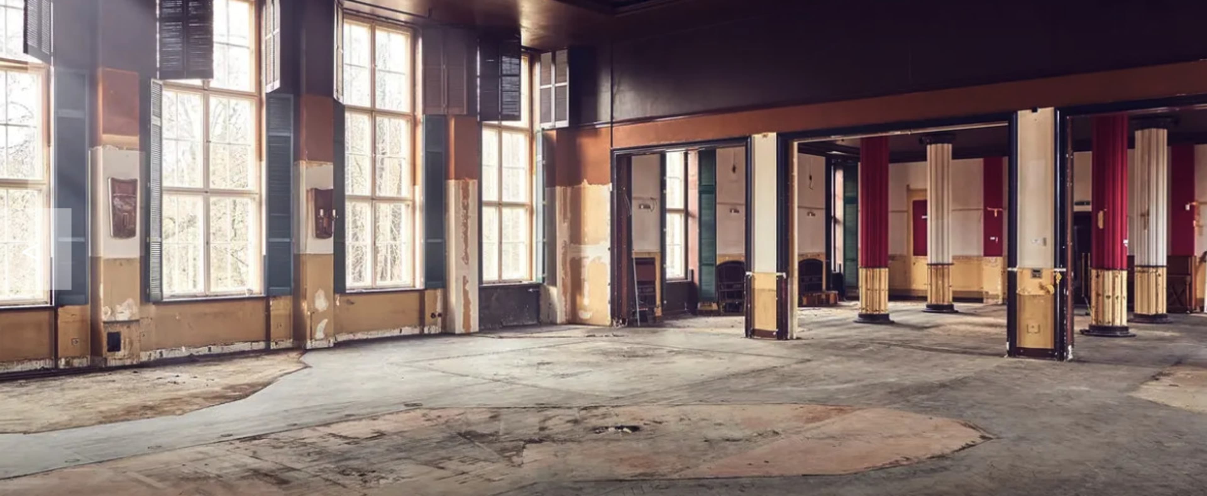 The image shows an empty, abandoned room with large windows and weathered walls, revealing signs of neglect.